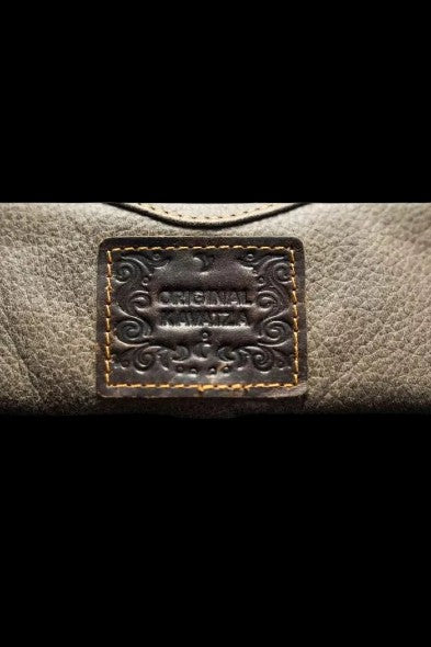 Close-up of a leather cannabis accessory case with ornate stitching and a label reading "Original Rawzda."