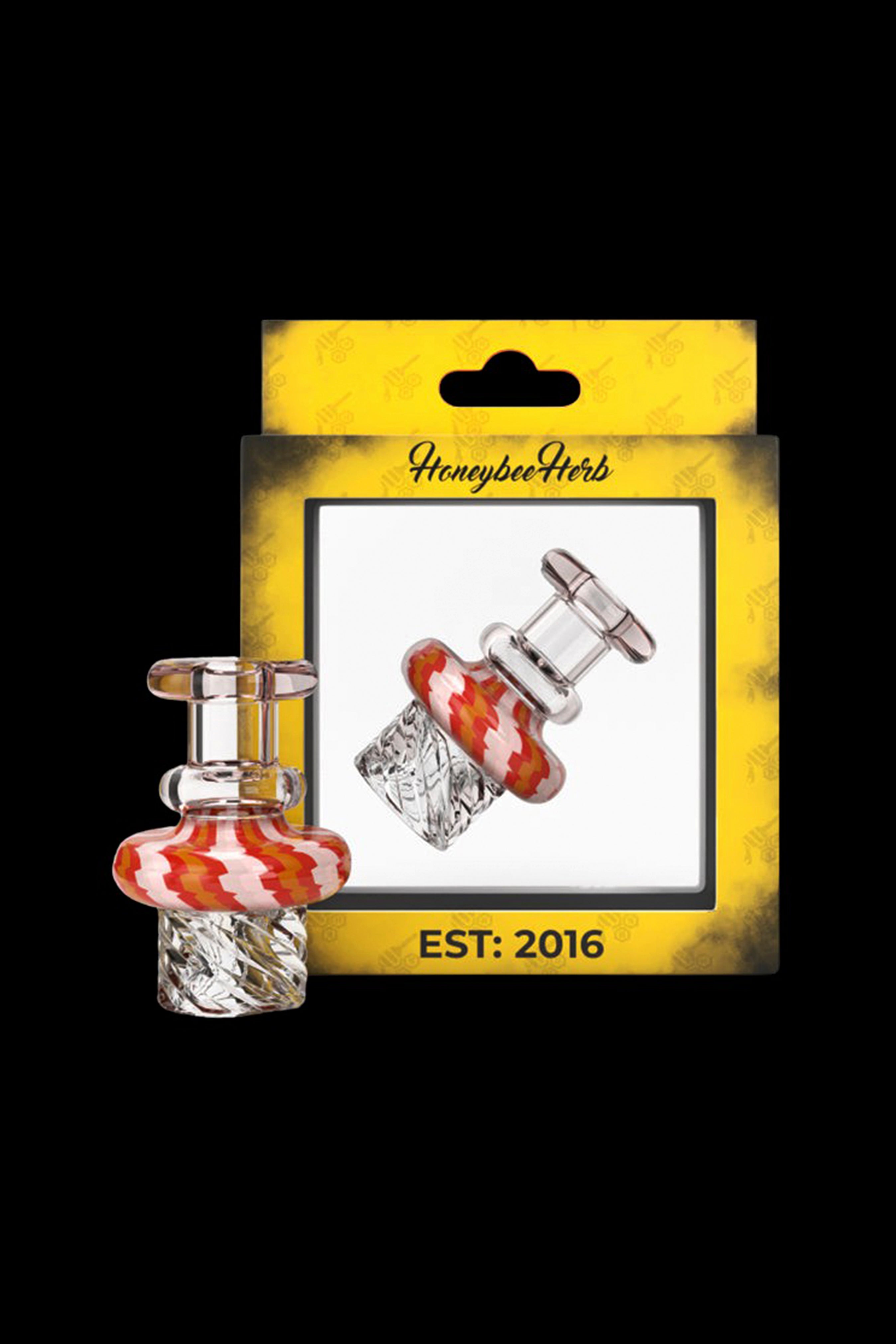 Glass dab rig water pipe with red and white swirls in packaging labeled "Honeybee Herbs EST: 2016".