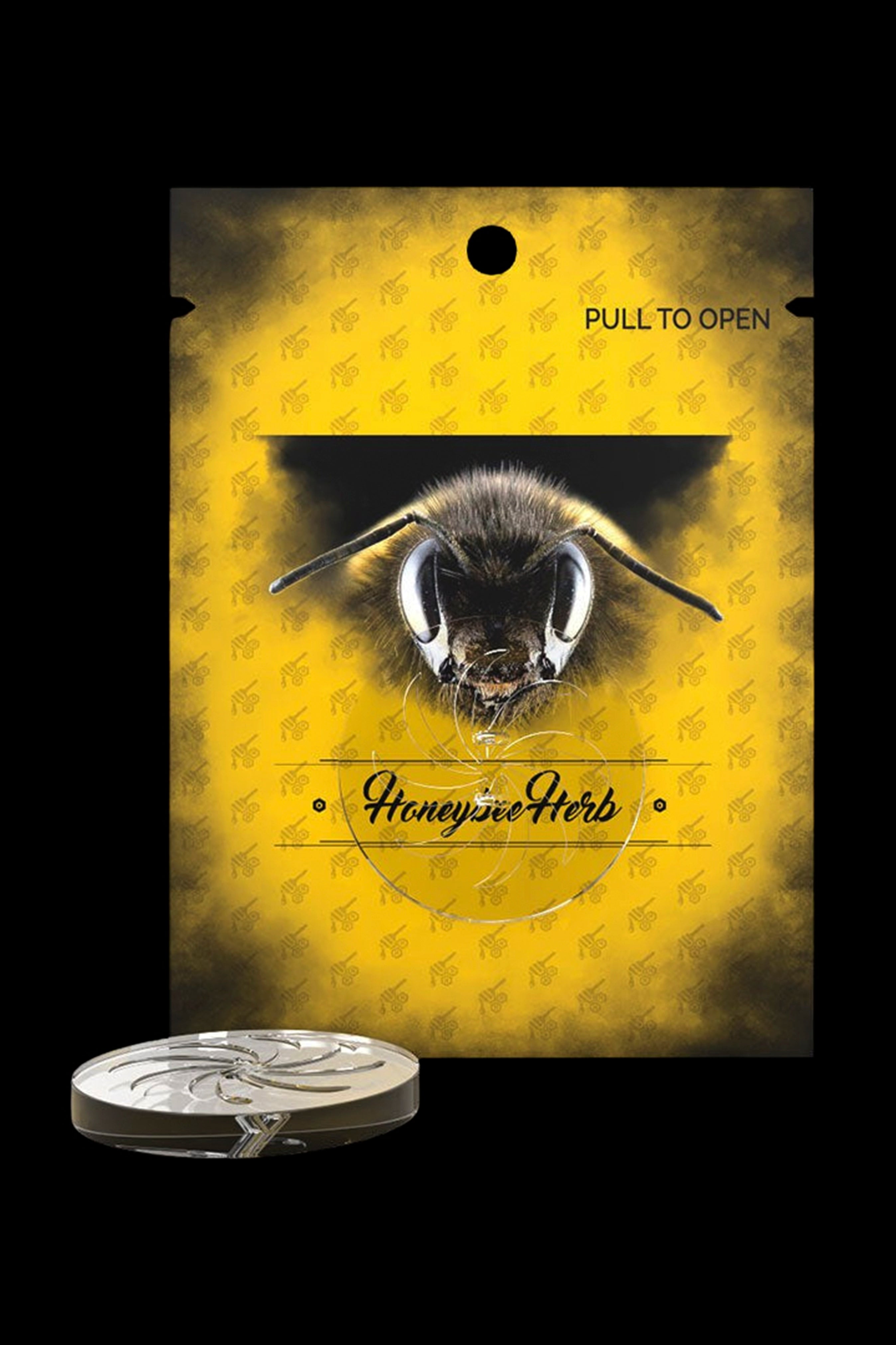 Yellow cannabis packaging bag with a bee image and the text “Honeybee Herb” alongside a silver grinder.