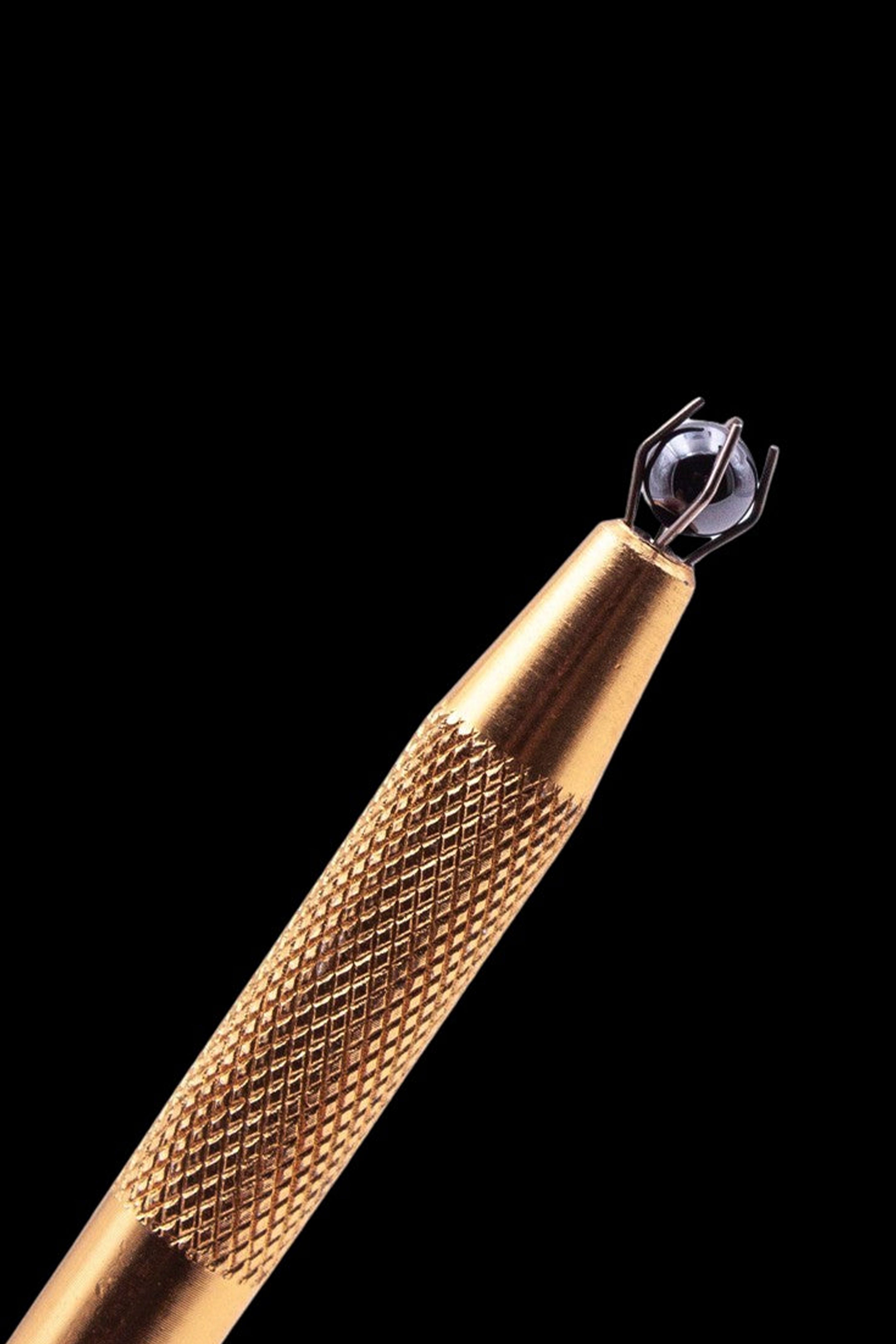 Close-up of a gold dab tool with a rounded tip.