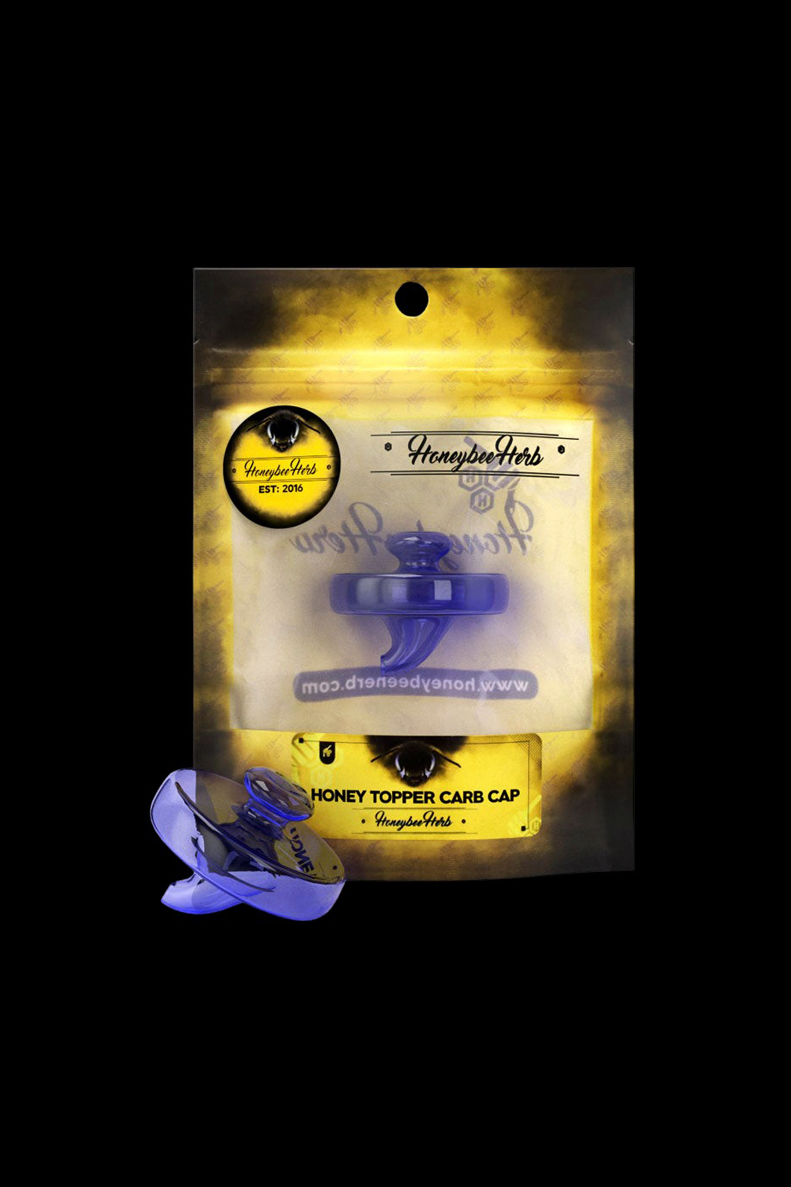 Close-up front view of the Honeybee Herb Honey Topper Carb Cap in translucent blue displayed against its yellow branded packaging.