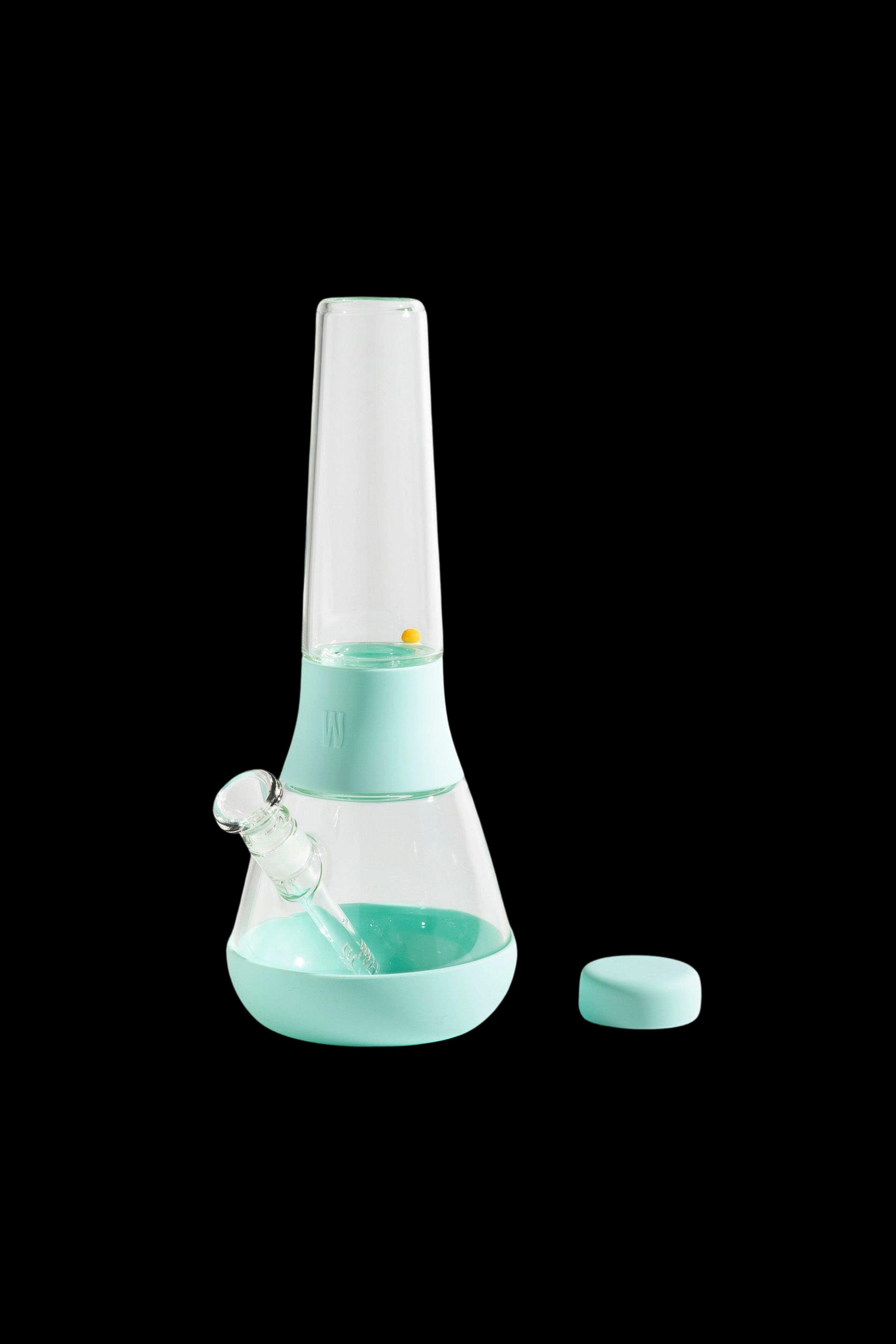 Mint green glass bong with silicone accents and cap, isolated on a black background.