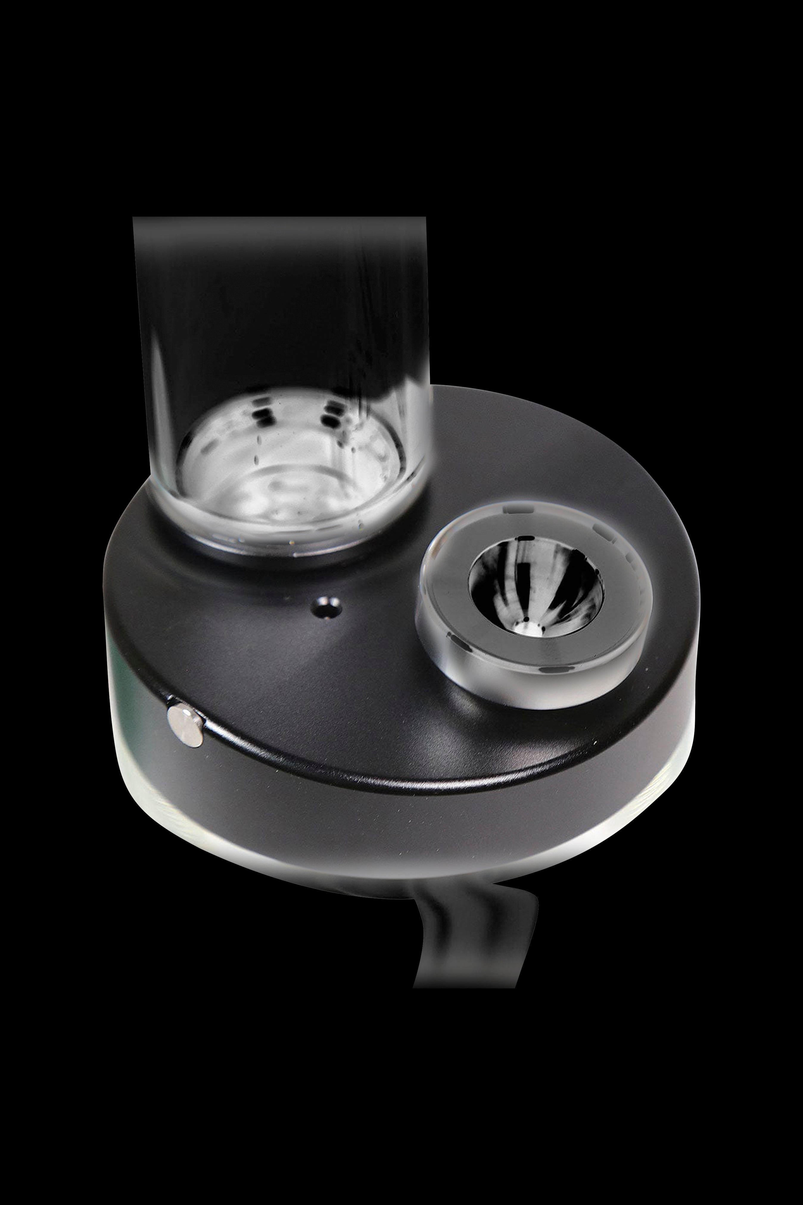 Black cannabis oil rig with glass bowl and carb cap, isolated on a black background.