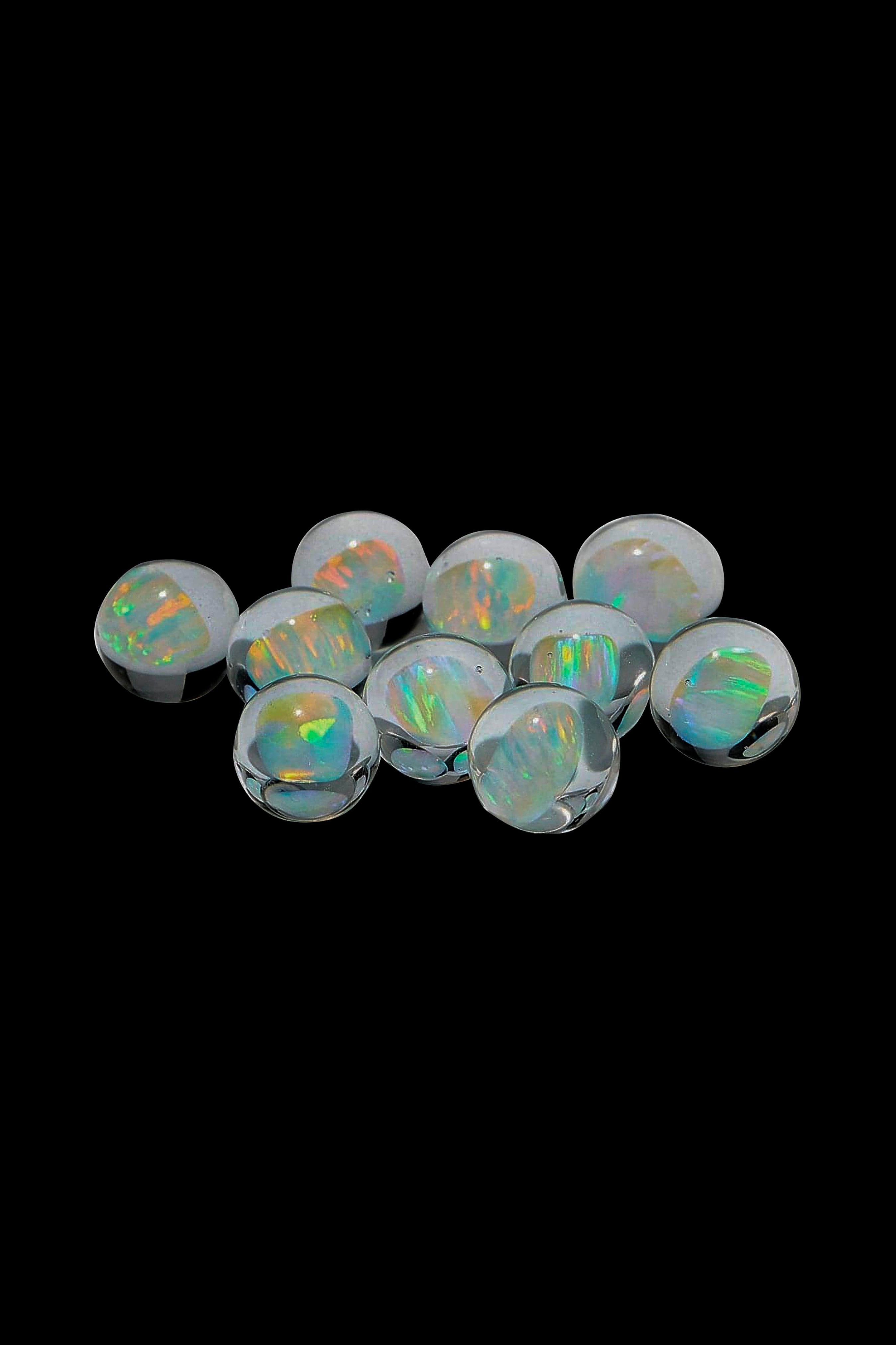 Iridescent opal cannabis smoking pearls scattered on a black background.