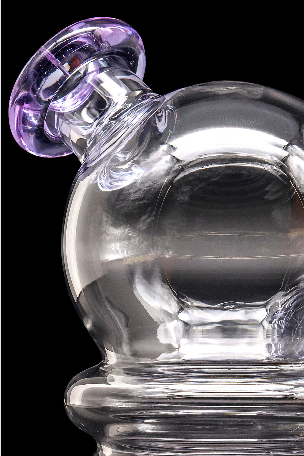 A clear glass dab rig with a purple-accented mouthpiece, showcasing swirling glass patterns.