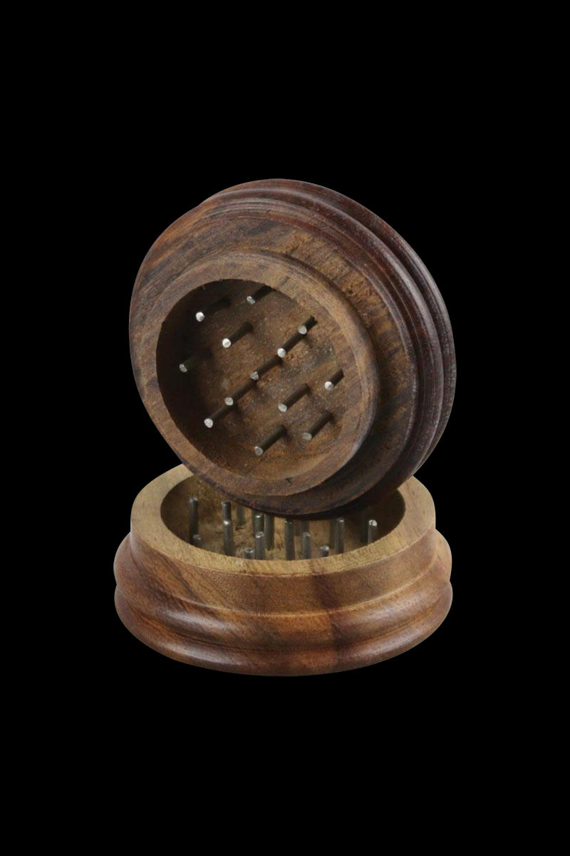 Angled close-up of the open Wood Grinder - Ben Franklin showing its carved wooden halves and metal grinding pins against a black background