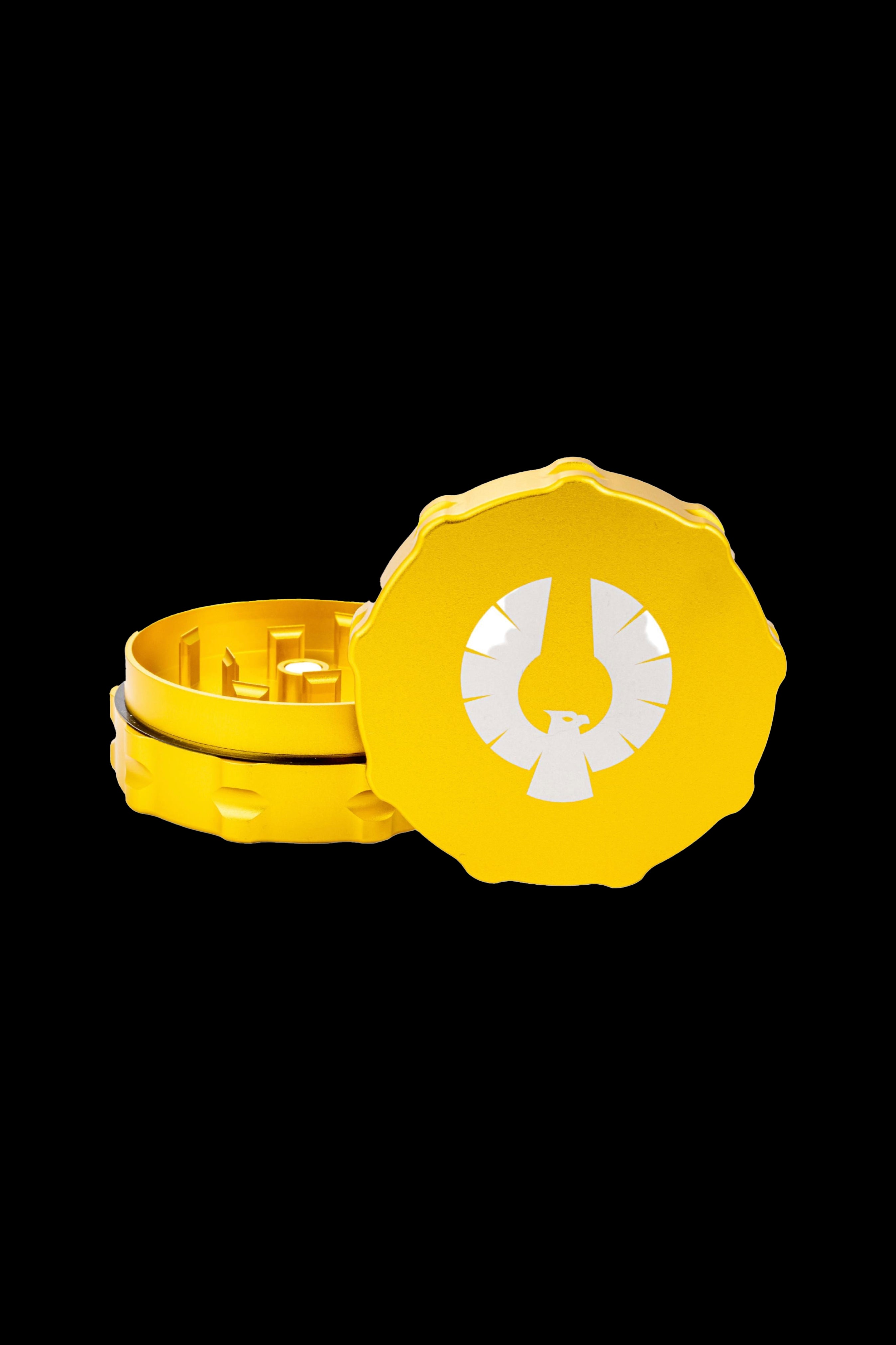 Yellow cannabis grinder with a branded lid, partially open to reveal internal grinding components.