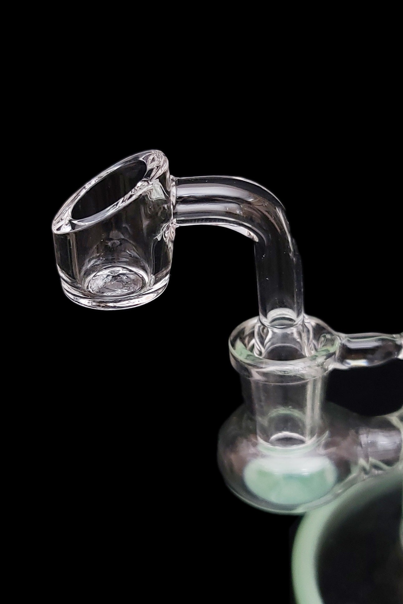 Clear glass dab rig with a quartz banger, isolated on a black background.