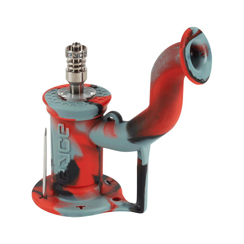 Angled close-up of an Rasta-colored EYCE Rig II Silicone Bong showing its curved mouthpiece, textured top cap, metal nail, and molded EYCE logo.