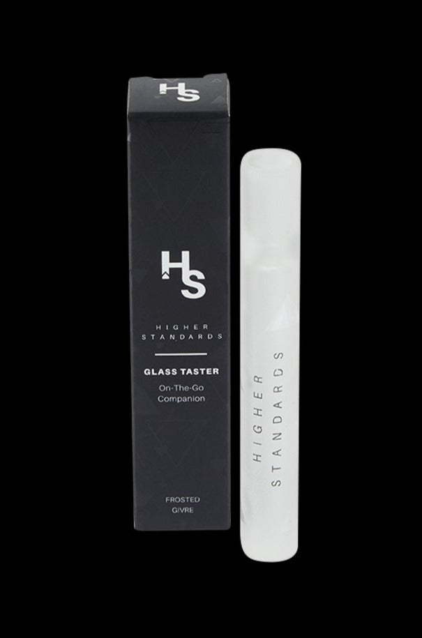 Studio-lit front view of the Higher Standards Glass Taster standing beside its dark branded box on a black background