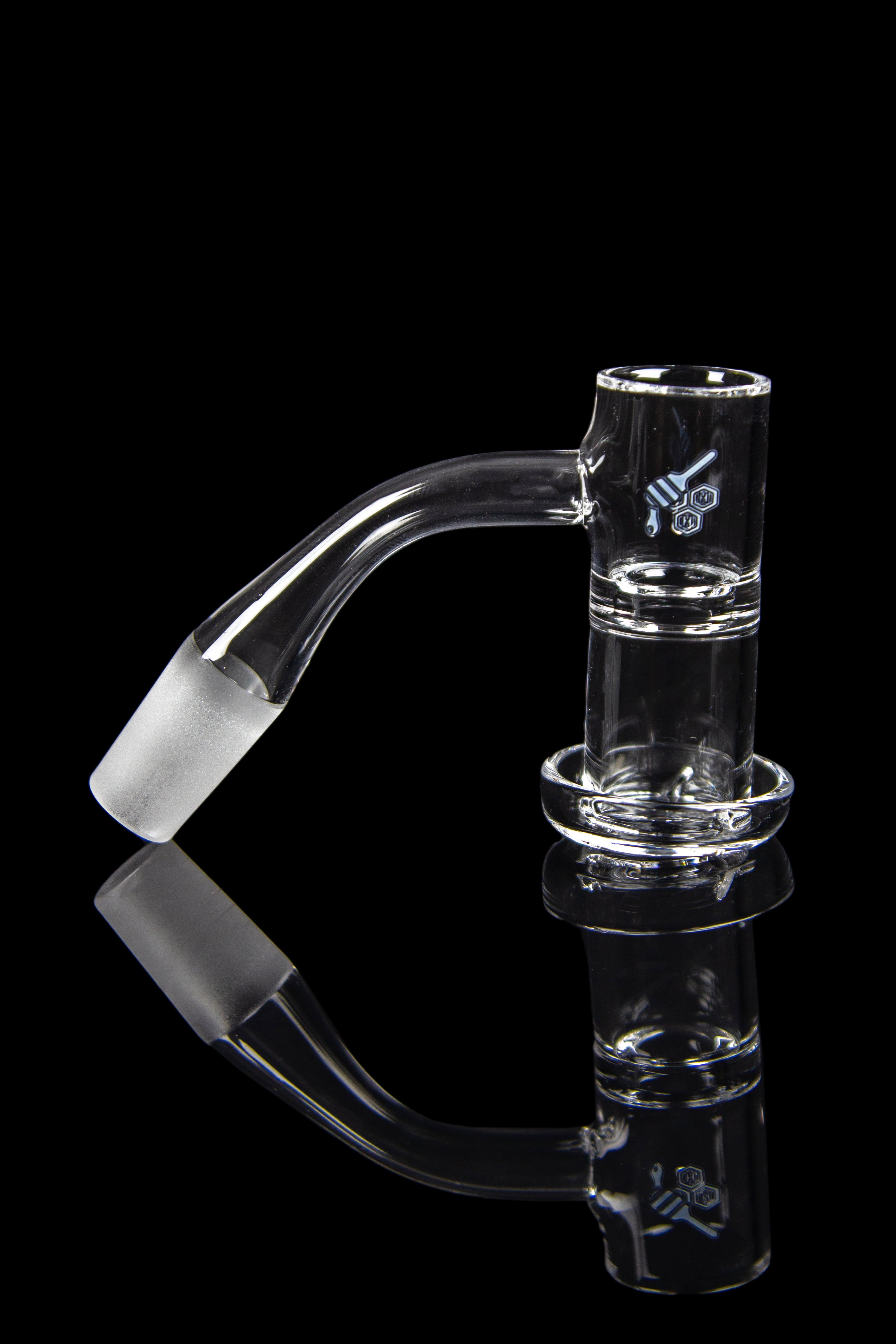 Clear glass dab rig with a bent neck and accompanying nail, reflected on a black surface.