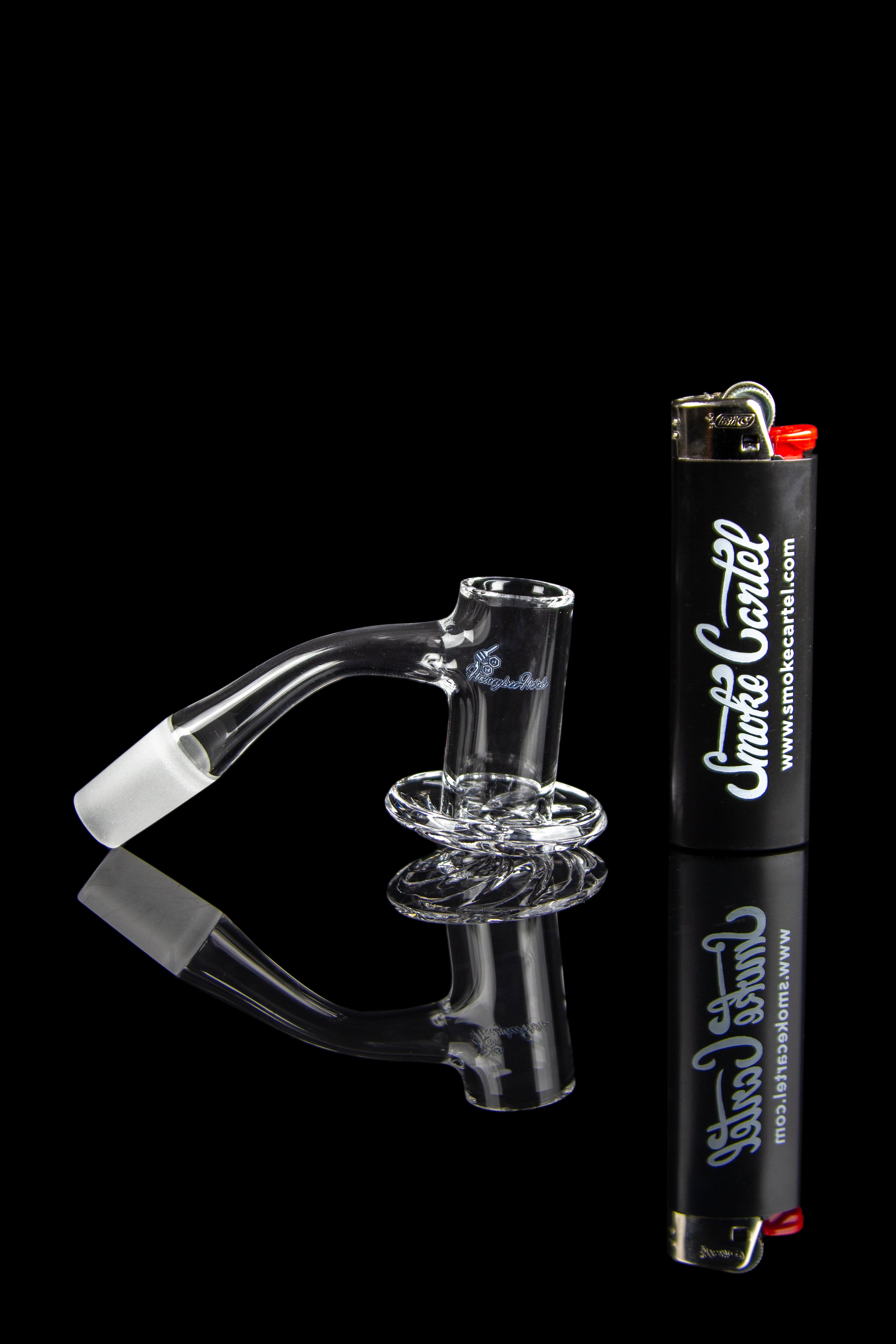 Clear glass dab rig with a quartz insert, alongside a lighter and branding for Smoke Cartel.