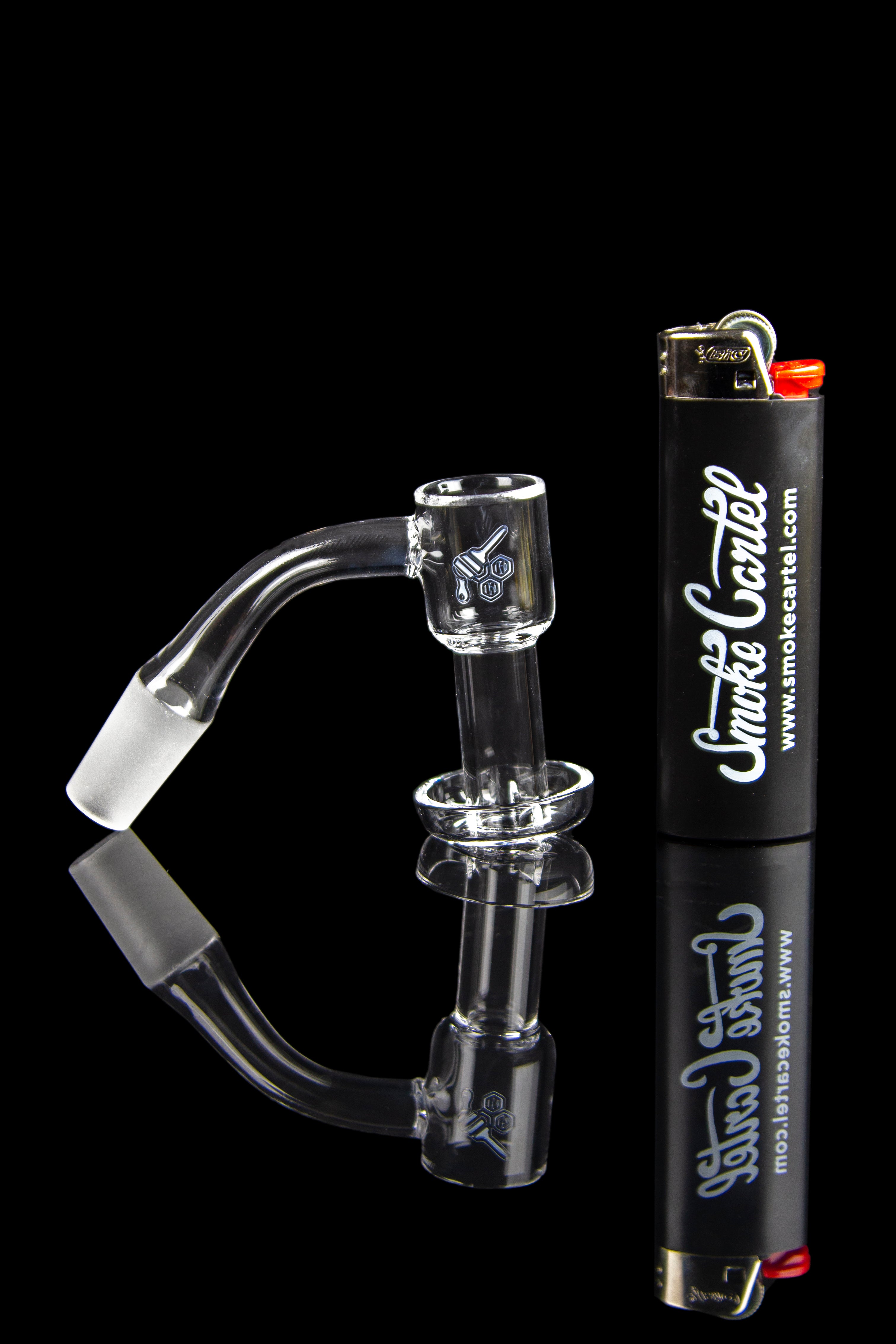 Clear glass dab rig with a quartz banger, alongside a lighter, branded with "Smoke Cartel."
