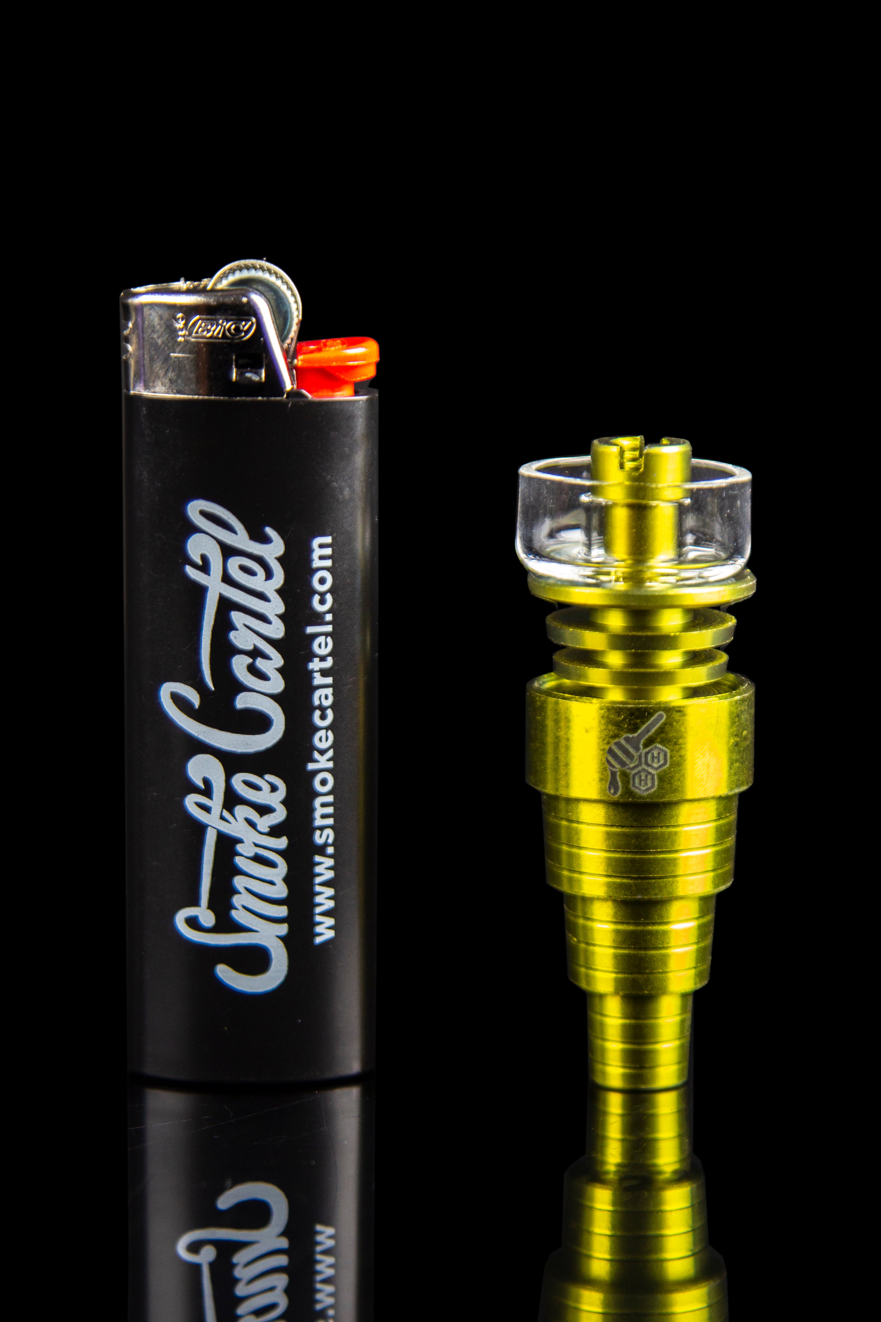 Gold oil burner pipe and branded lighter on a reflective black surface.