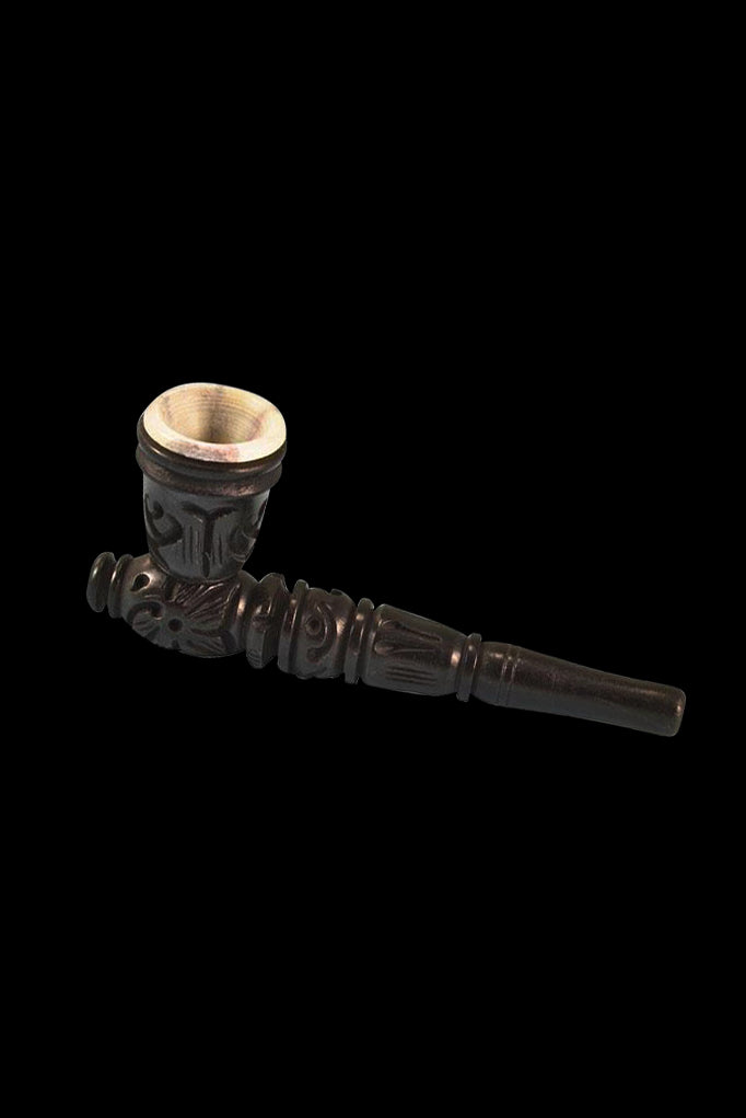 Ornate, dark wooden pipe with a carved design, isolated on a black background.