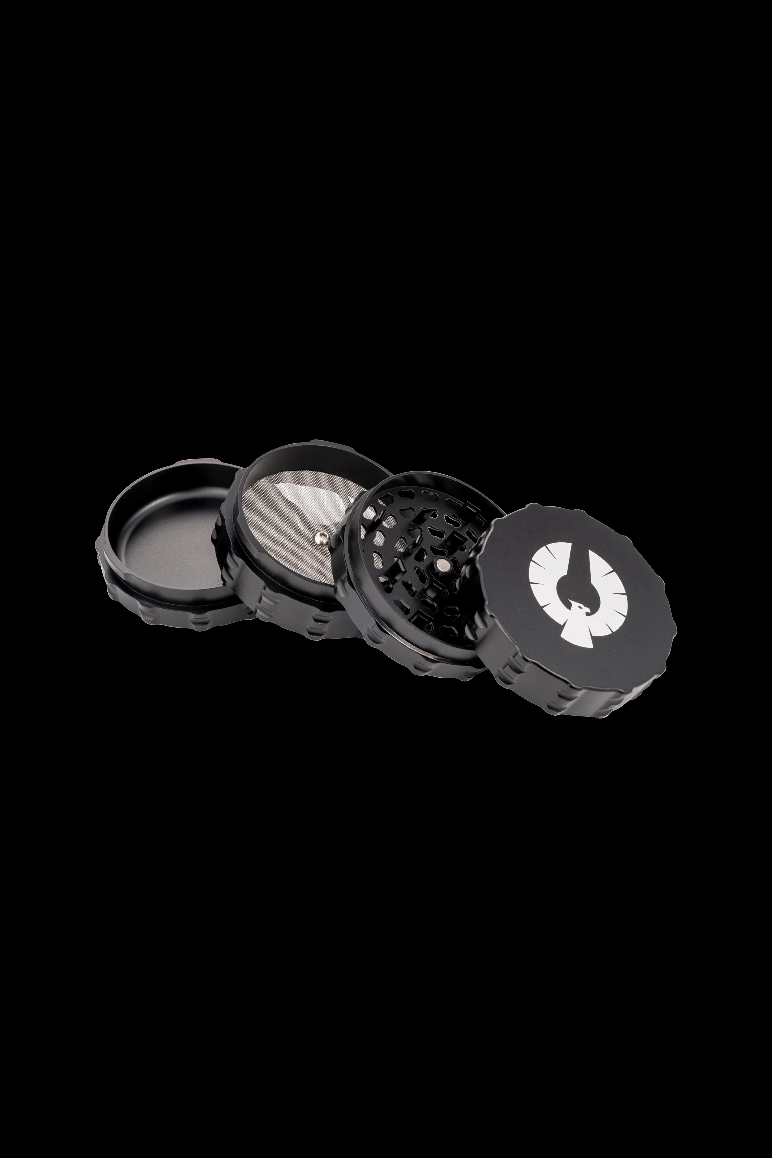 Black four-piece cannabis grinder with a white logo, disassembled to show internal components.