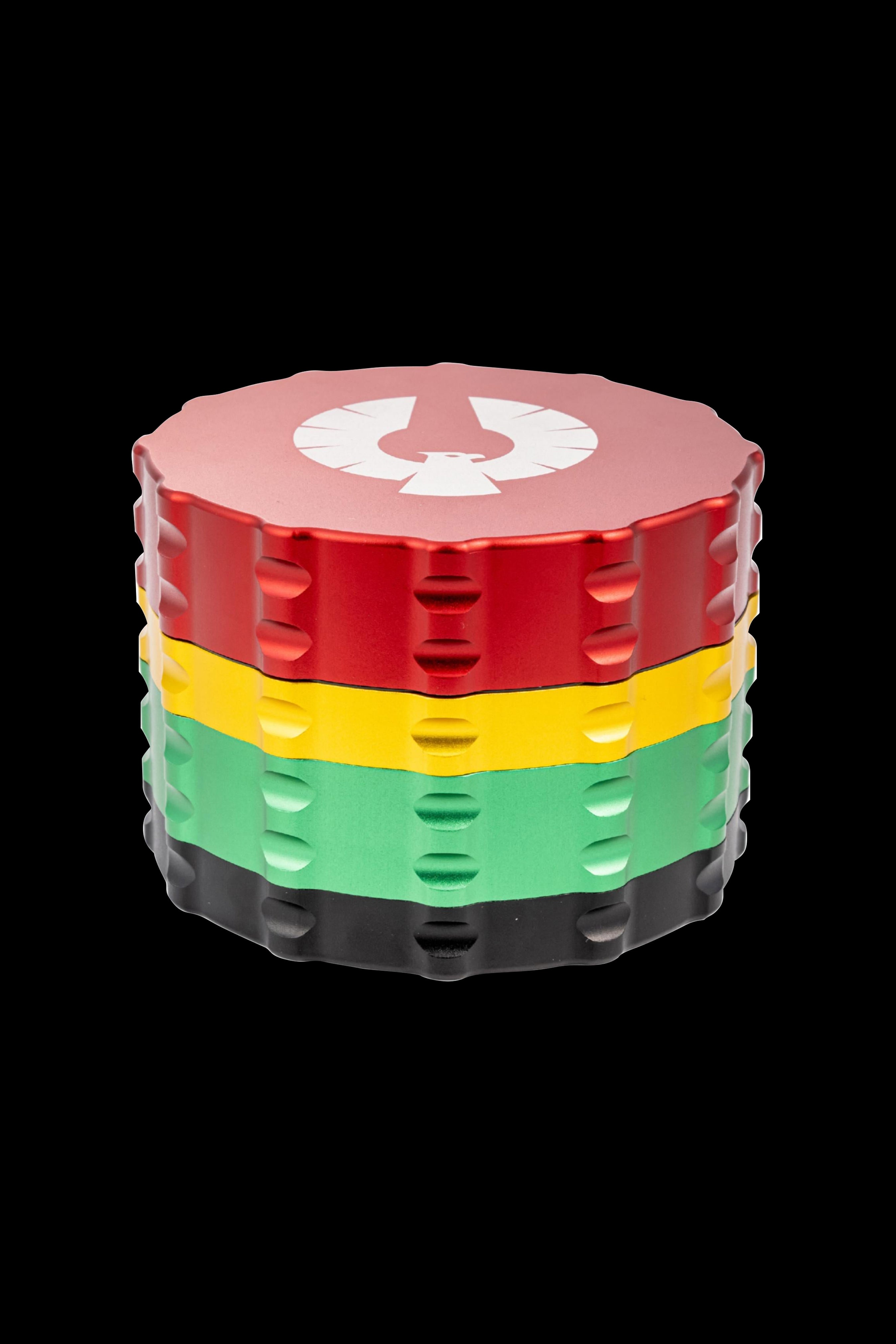Four-layer metal grinder with red, yellow, green, and black tiers, featuring a white emblem on the lid.