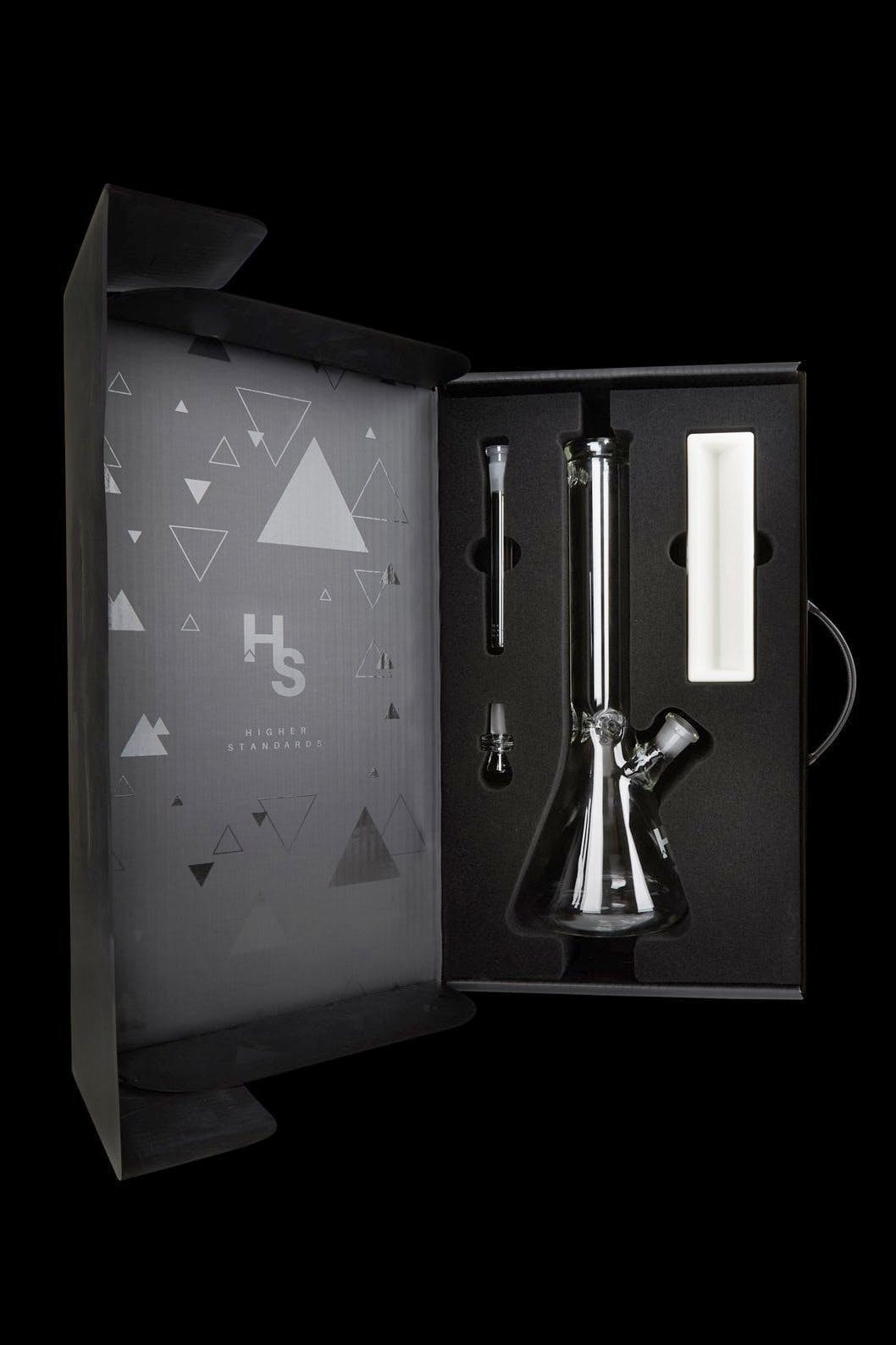 A glass bong displayed in a black, patterned box with the “HS” logo for Higher Standards.