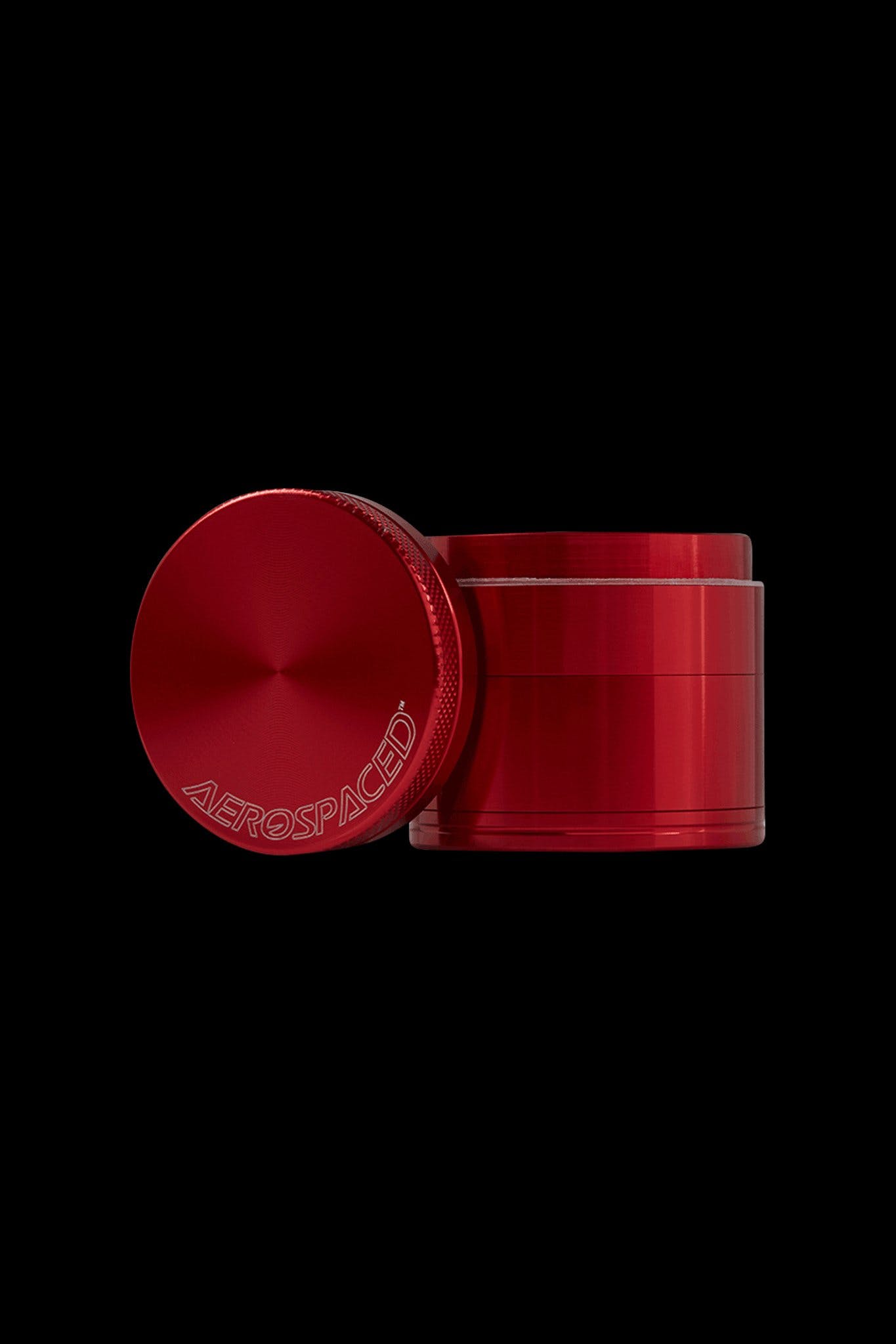 Red four-piece metal grinder with “AEROSPACED” logo, isolated on black.