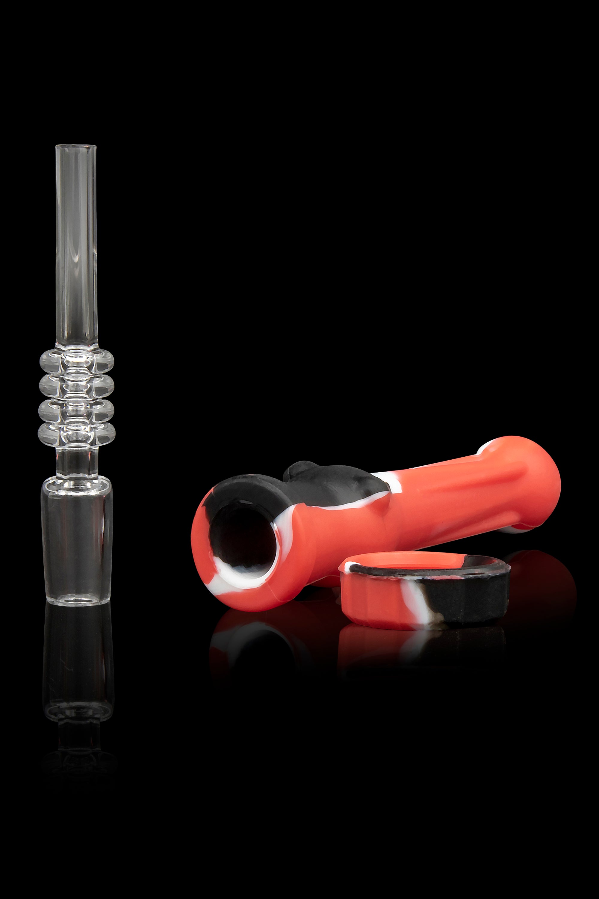 Glass oil rig and silicone hand pipe with a collection cup, studio shot on a reflective black surface.