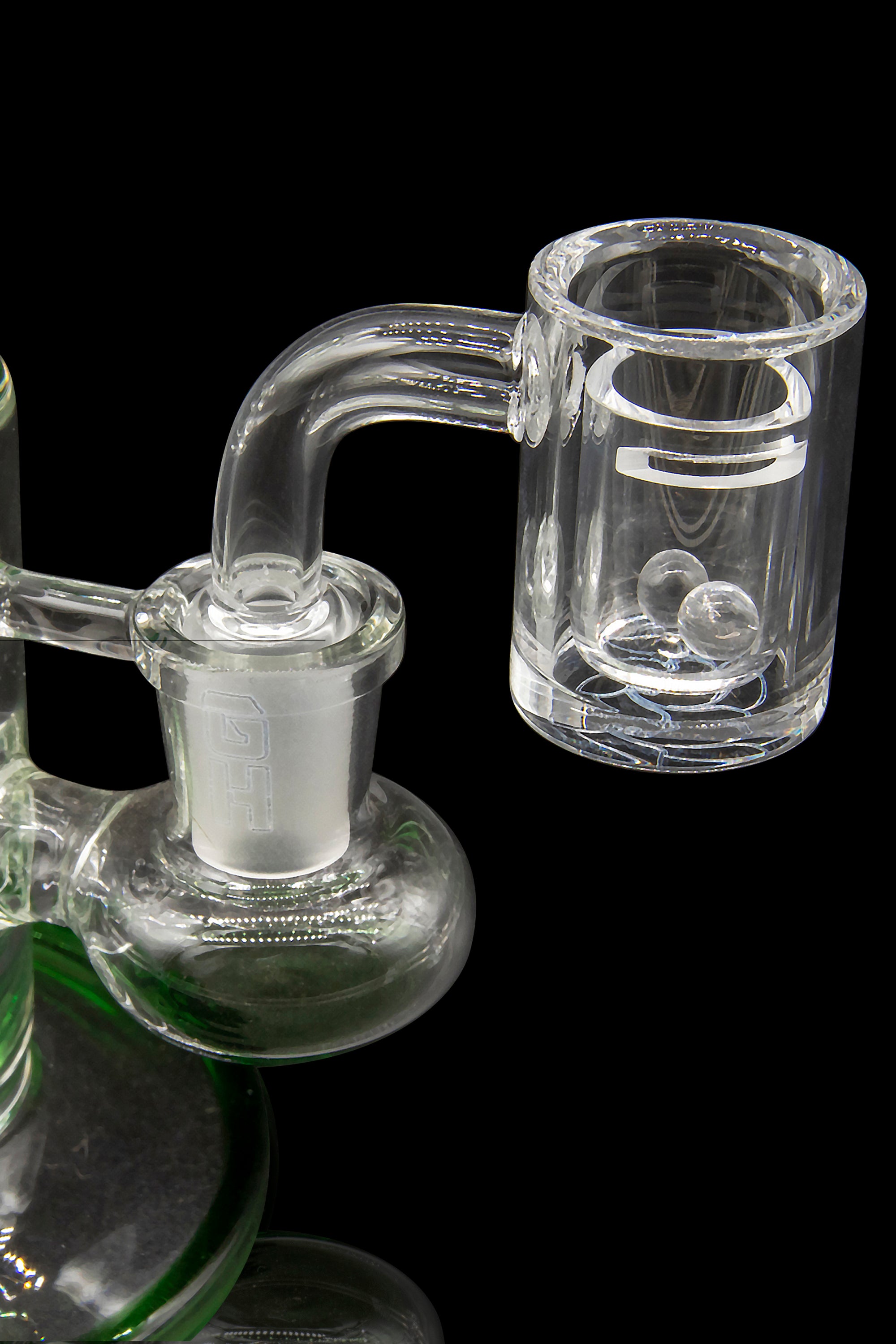 Clear glass dab rig with a quartz banger, isolated on a black background.