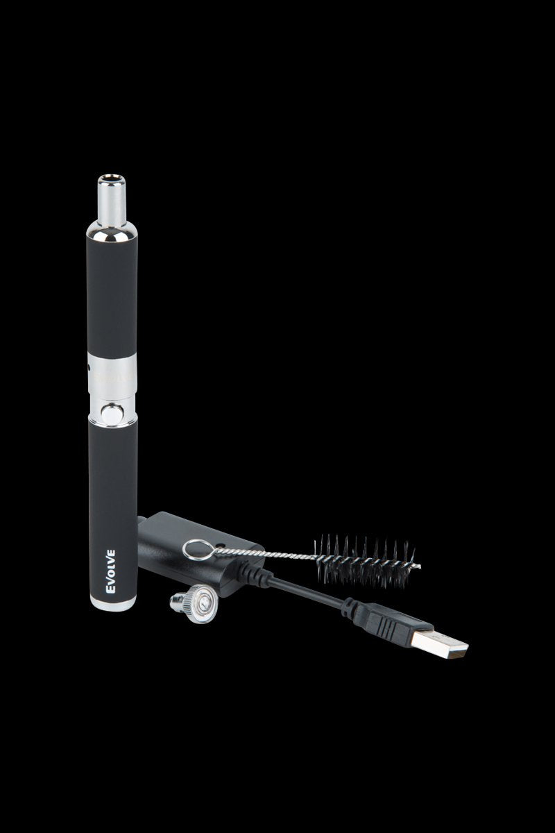 Vertical three-quarter view of a silver Yocan Evolve-D Dry Herb Vaporizer Pen standing beside its USB charger, brush, and mouthpiece on a black background.