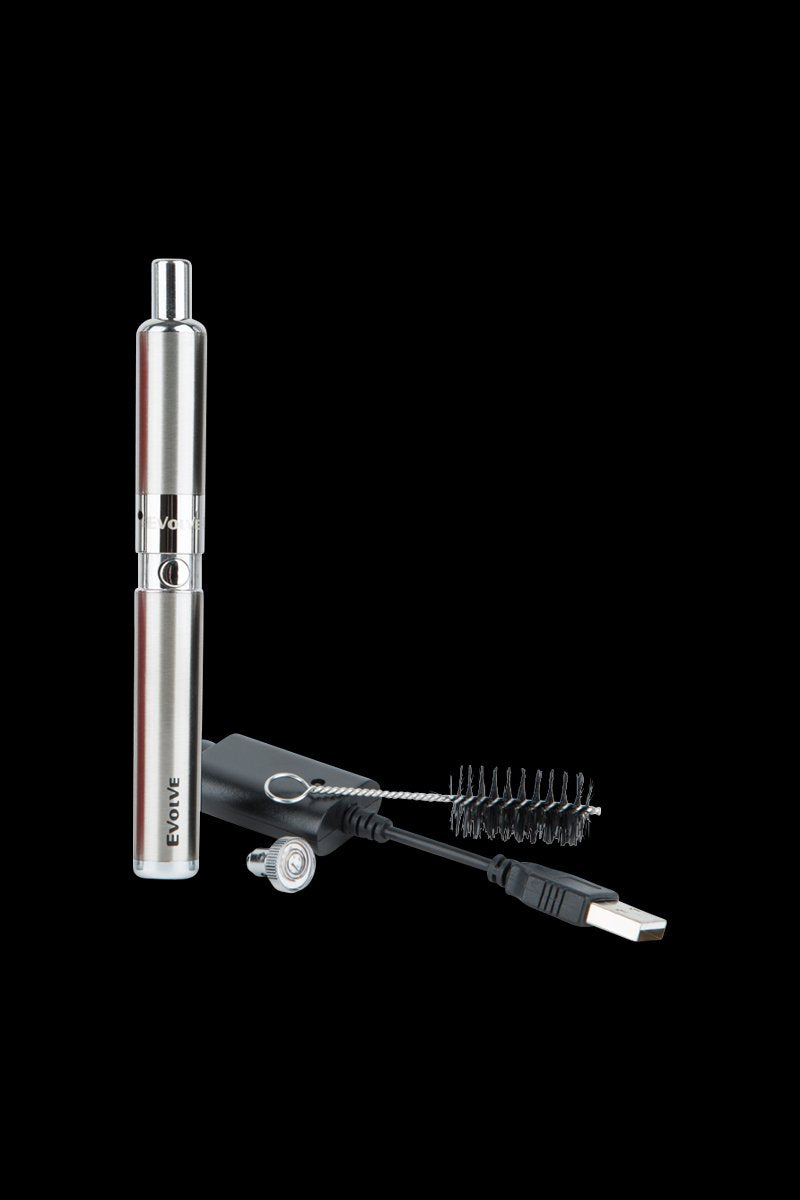 Vertical studio shot of a silver Yocan Evolve-D Dry Herb Vaporizer Pen standing beside its USB charger, cleaning brush, and mouthpiece on black background