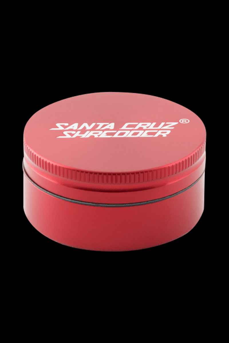 Front-facing close-up of a matte red Santa Cruz Shredder 2-Piece Grinder on a black background, showing the textured lid edge and white logo.