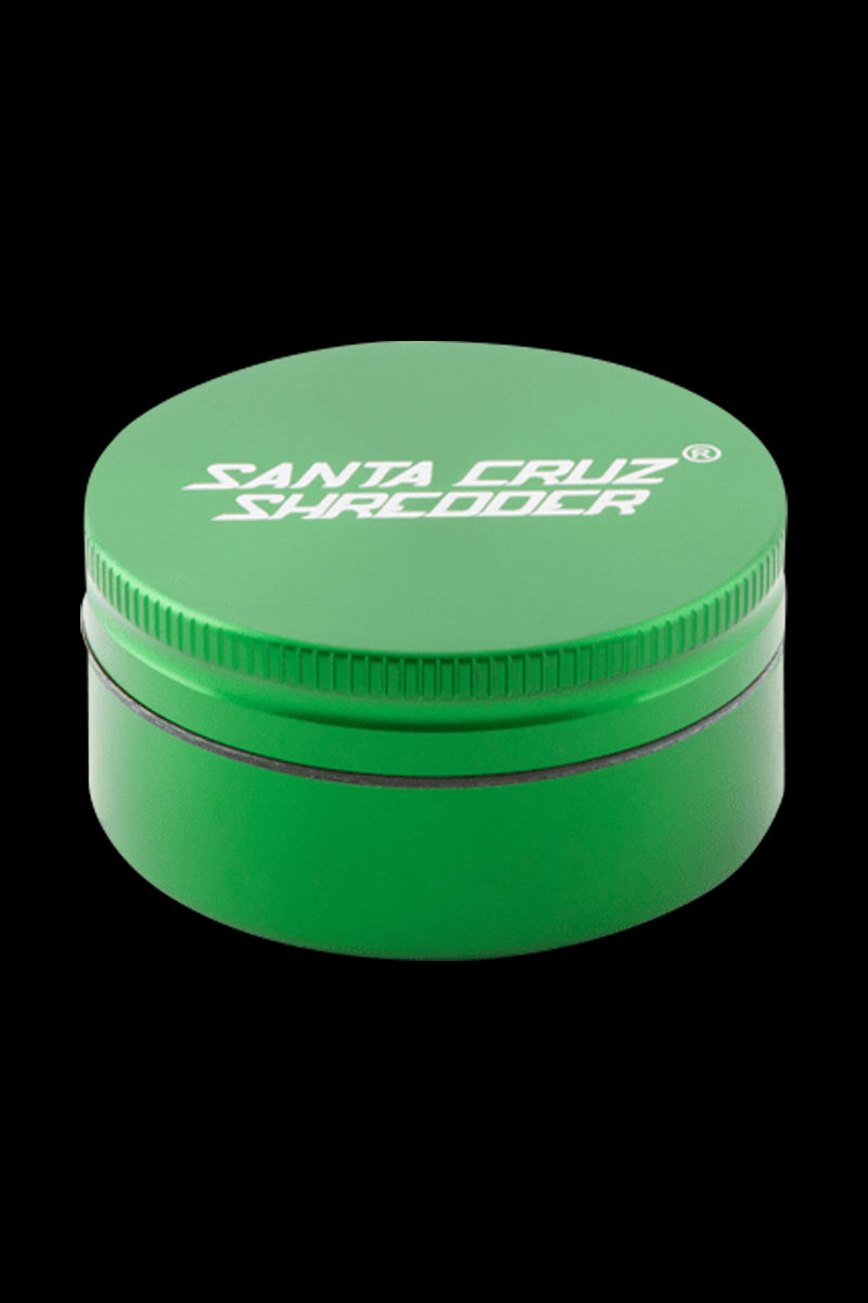 Top-down close-up of the green Santa Cruz Shredder 2-Piece Grinder against a black background showing its ridged lid and white logo.