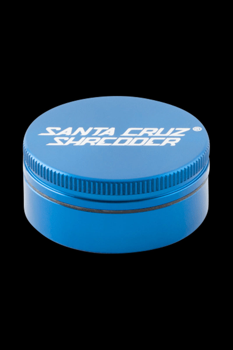 Top-down view of a blue Santa Cruz Shredder 2-Piece Grinder with white logo on the lid against a black background.
