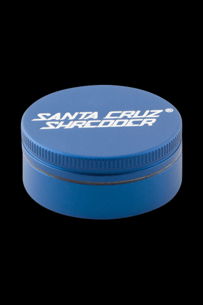 Top-down view of a small blue Santa Cruz Shredder 2-Piece Grinder centered on a black background, showing the white logo on the lid.