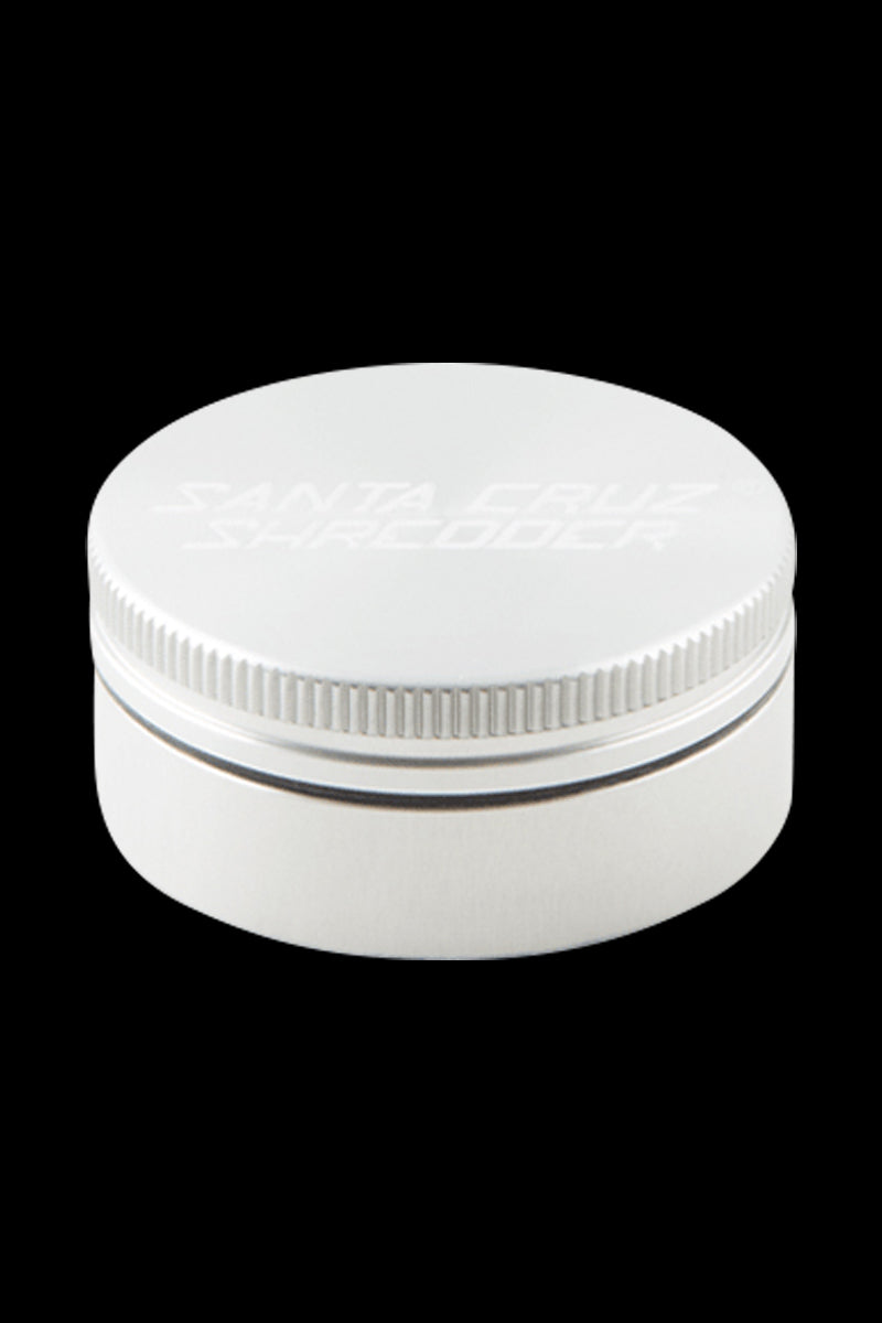 Top-down view of a small gold Santa Cruz Shredder 2-Piece Grinder centered on a black background, showing its textured lid edge and subtle logo.