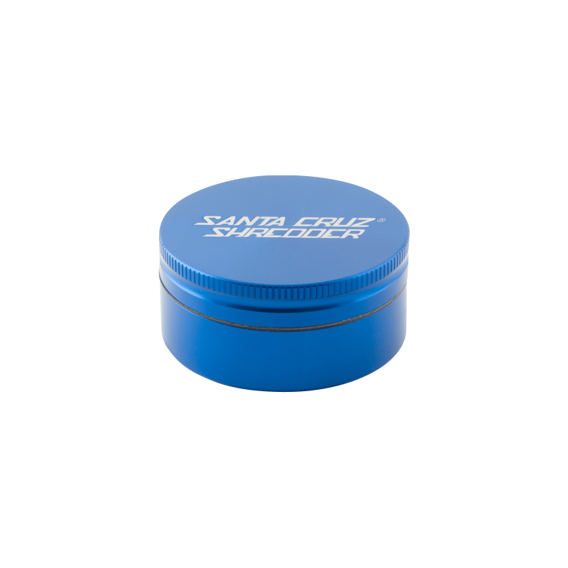 Top-down angled view of a small blue Santa Cruz Shredder 2-Piece Grinder with white logo on the lid and subtle shadow beneath