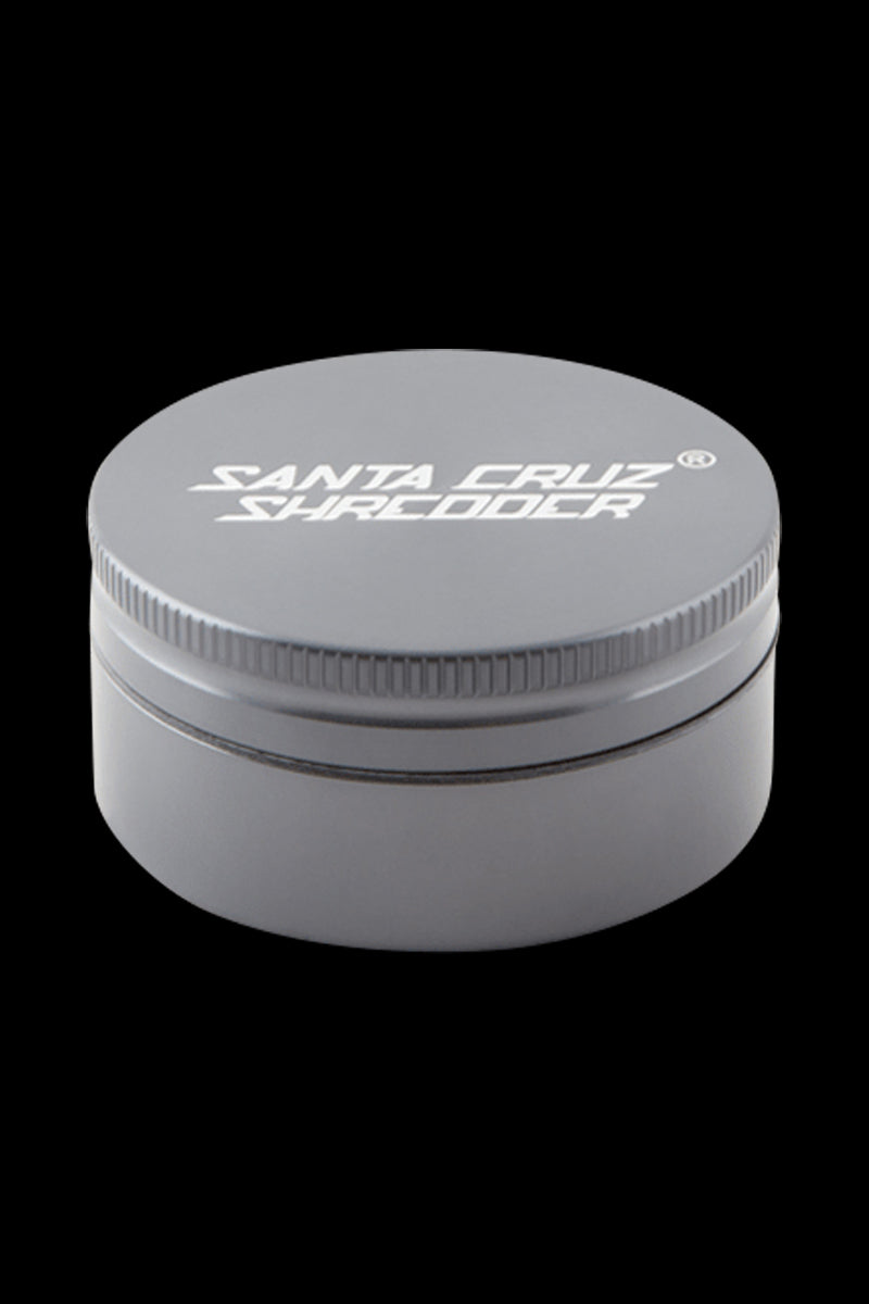 Top-front view of a small red Santa Cruz Shredder 2-Piece Grinder centered on a black background, showing the ridged lid edge and white logo.