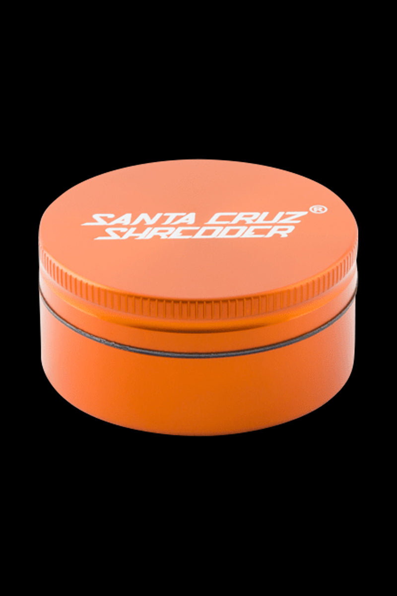 Close-up front view of a small green Santa Cruz Shredder 2-Piece Grinder centered on a black background, showing its lid logo and knurled edge.