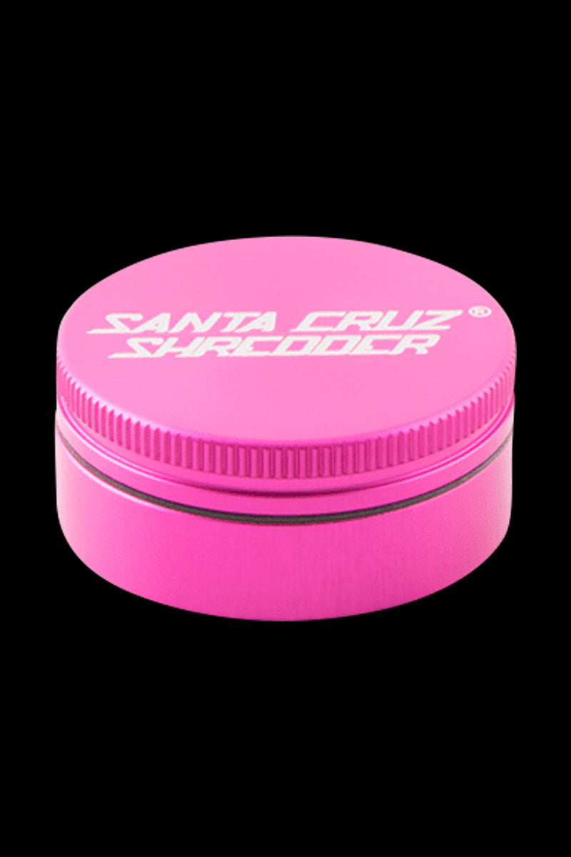 Top-down view of a matte pink Santa Cruz Shredder 2-Piece Grinder centered against a black background, showing the textured lid and white logo.