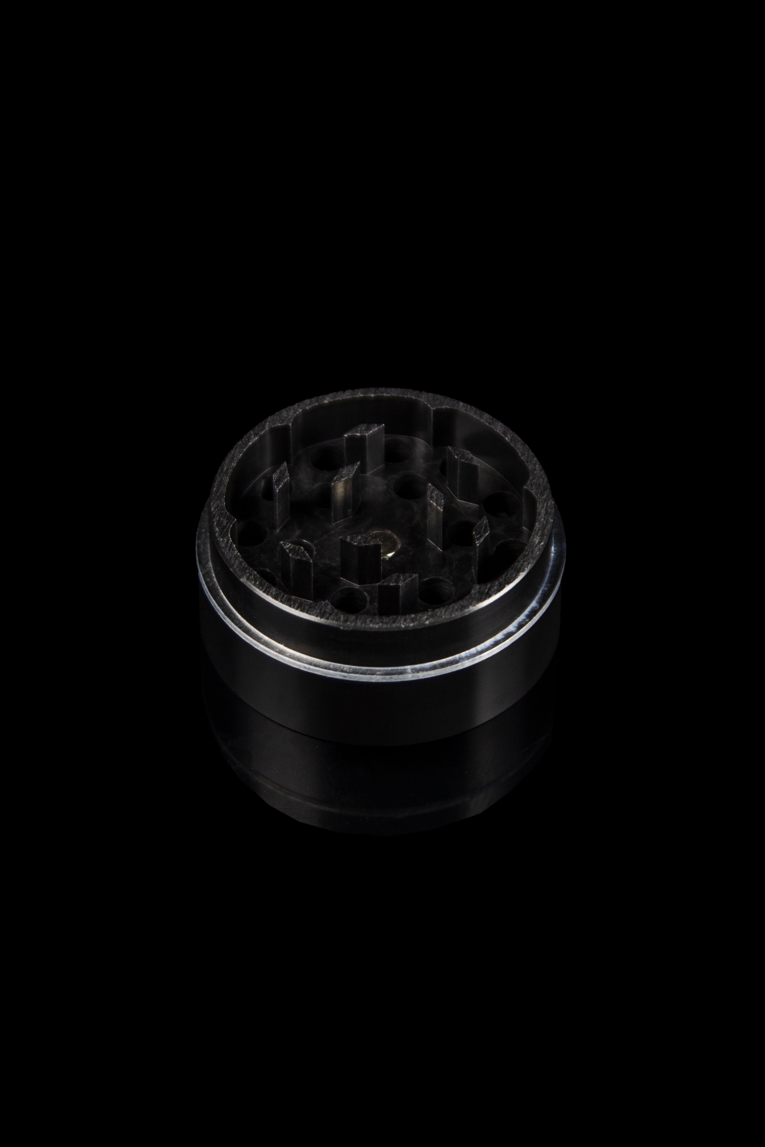 Metal cannabis grinder isolated on a black background.