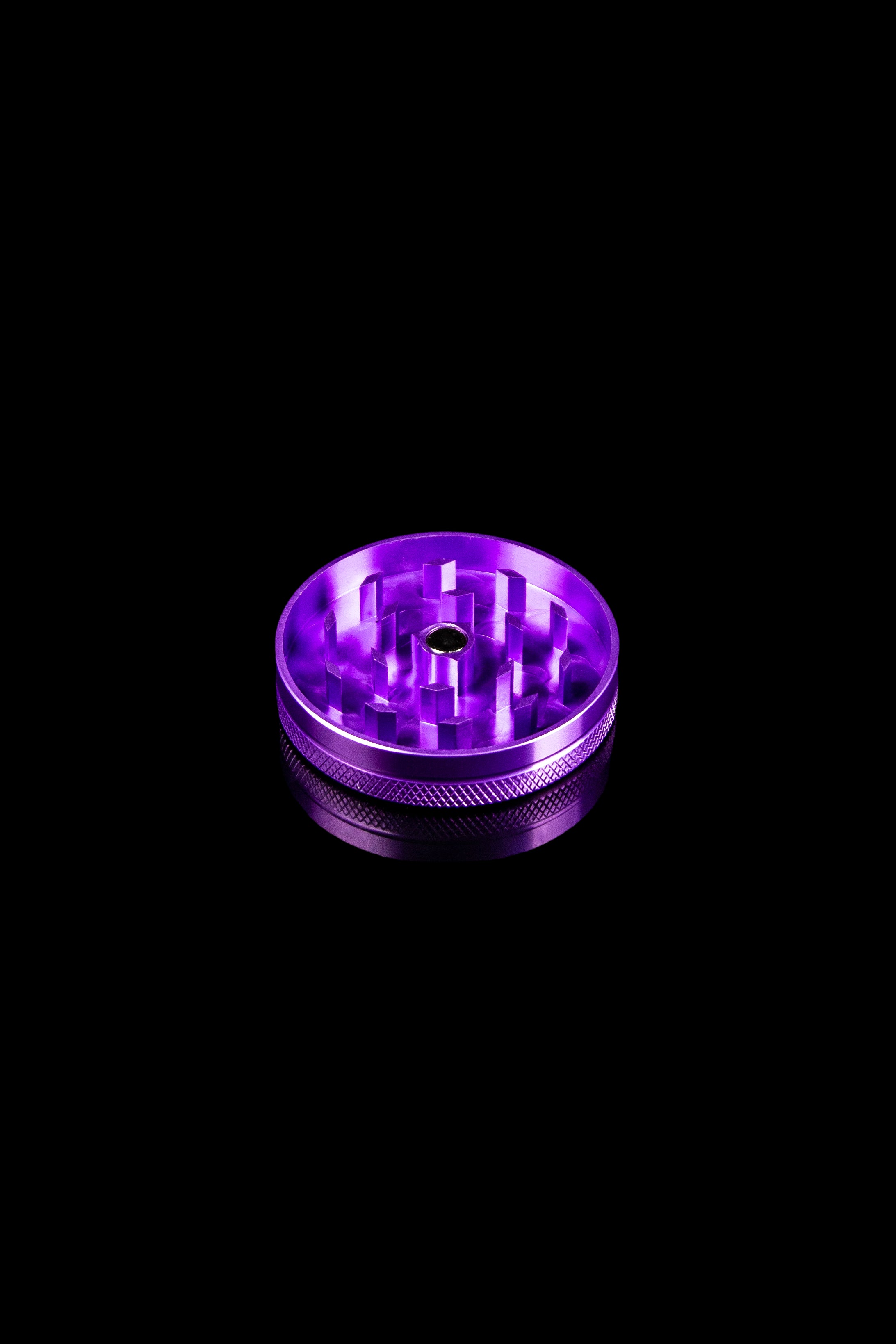 Purple metal cannabis grinder on a black background.