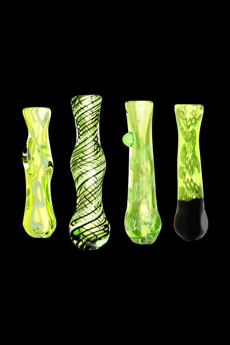 Four upright Acid Green Worked Glass Taster Chillum pieces on a black background, shown frontally with varied squiggles-in-black patterns and bulbous midsections.