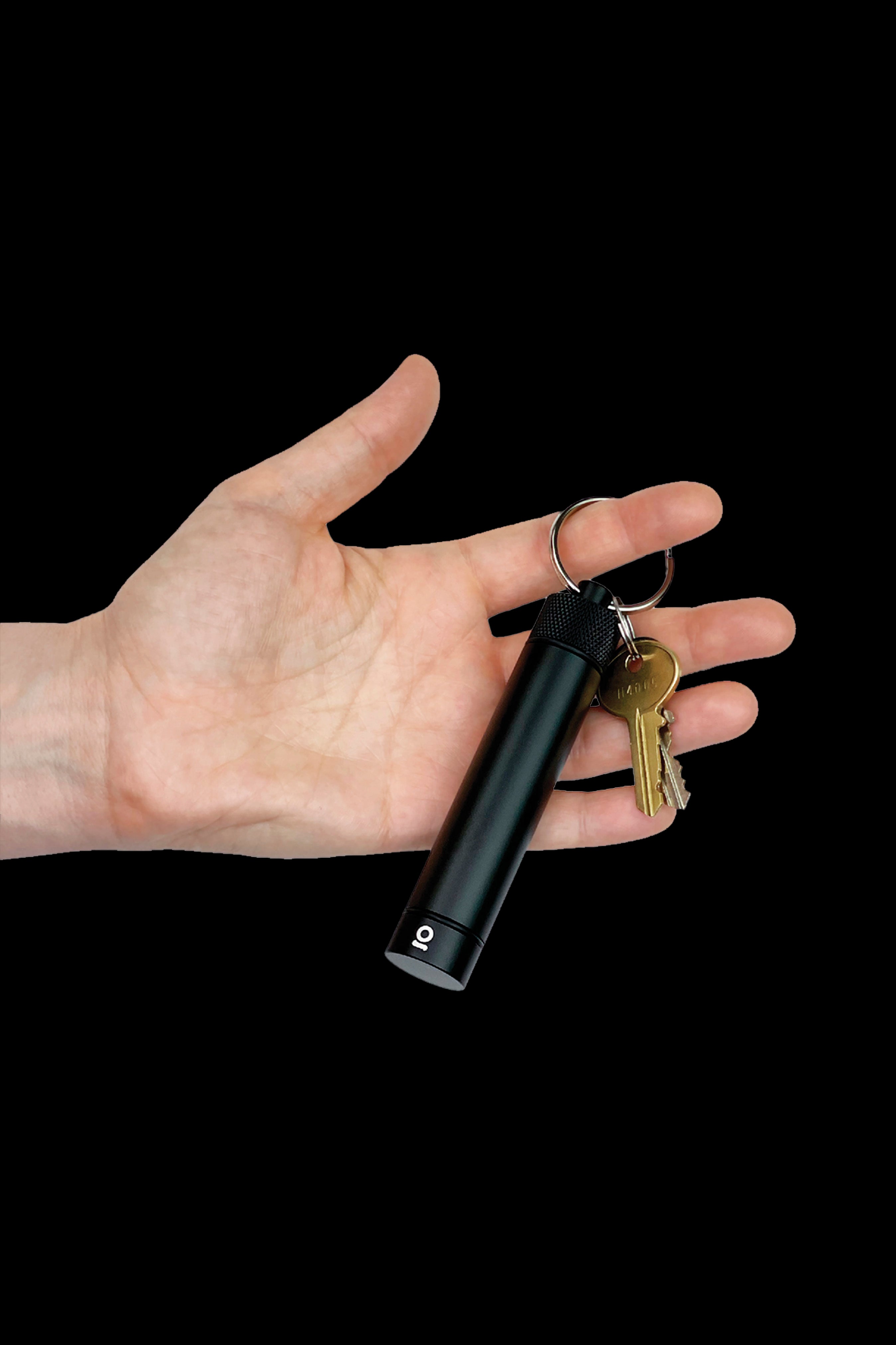 A hand displaying a black, cylindrical cannabis vaporizer with a keychain attached.