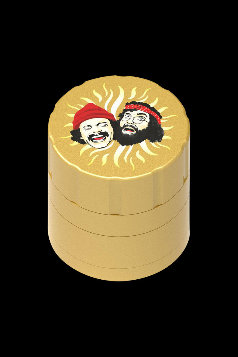 Front view of the Cheech & Chong 40th Anniversary Grinder, featuring cartoon portraits on a golden metallic finish.