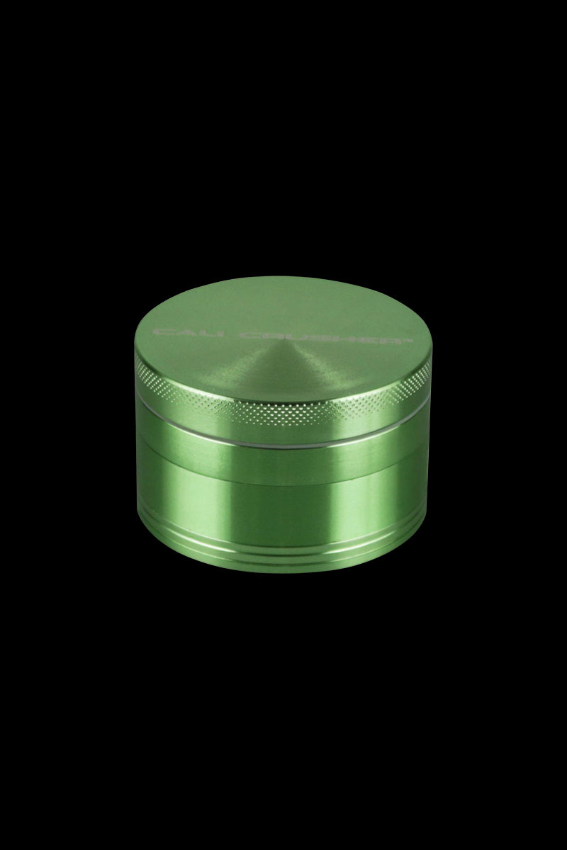A centered, angled view of the Cali Crusher O.G. 4-Piece Grinder, showcasing its metallic finish and circular design.