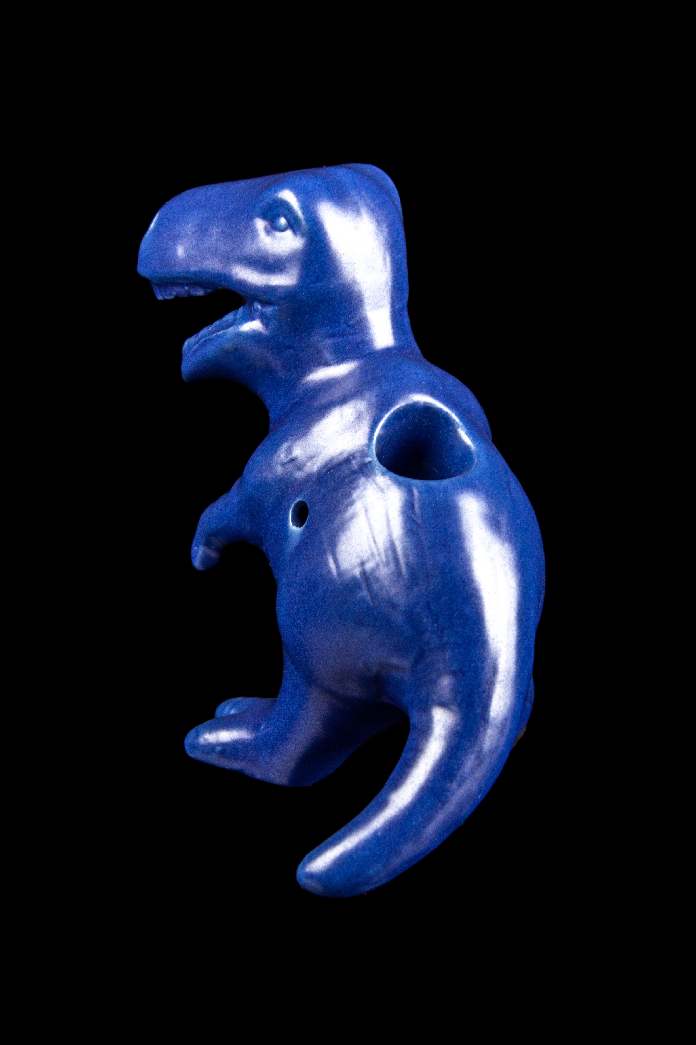 Blue glass Tyrannosaurus Rex-shaped pipe against a black background.