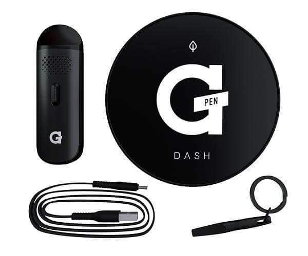 Top-down product layout showing the G Pen Dash Dry Herb Vaporizer with its black circular charging pad, compact black vaporizer, USB cable, keyring tool, and white logo on a white background.