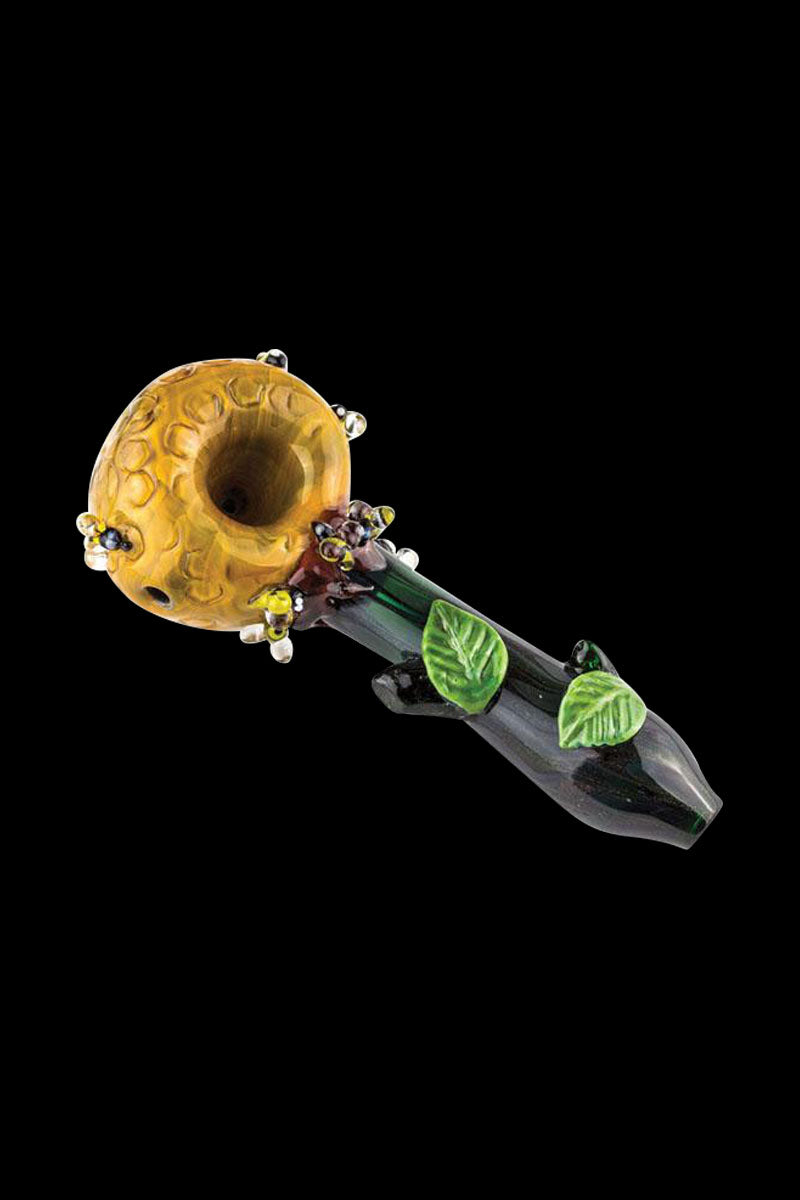 Angled close-up of the Empire Glassworks Small Spoon Pipe - Beehive showing a yellow honeycomb bowl with glass bead accents and a dark green stem with raised leaves