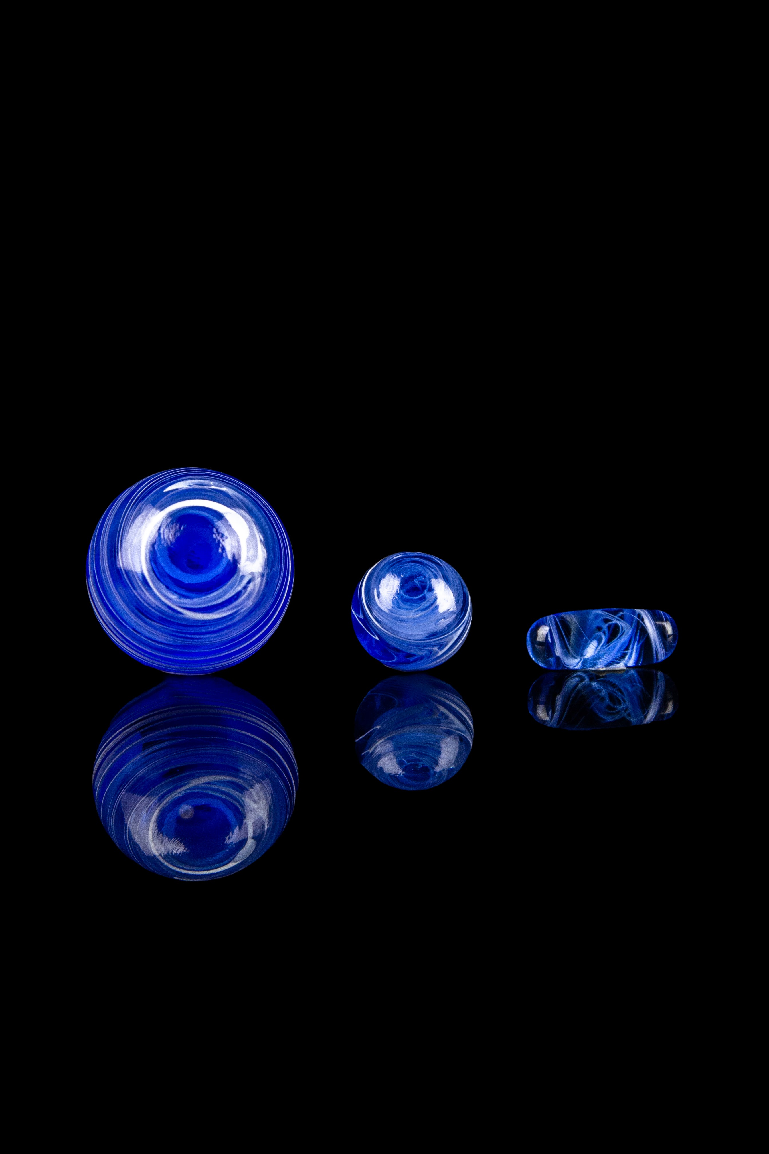 Blue glass cannabis water pipes and accessories on a black reflective surface.
