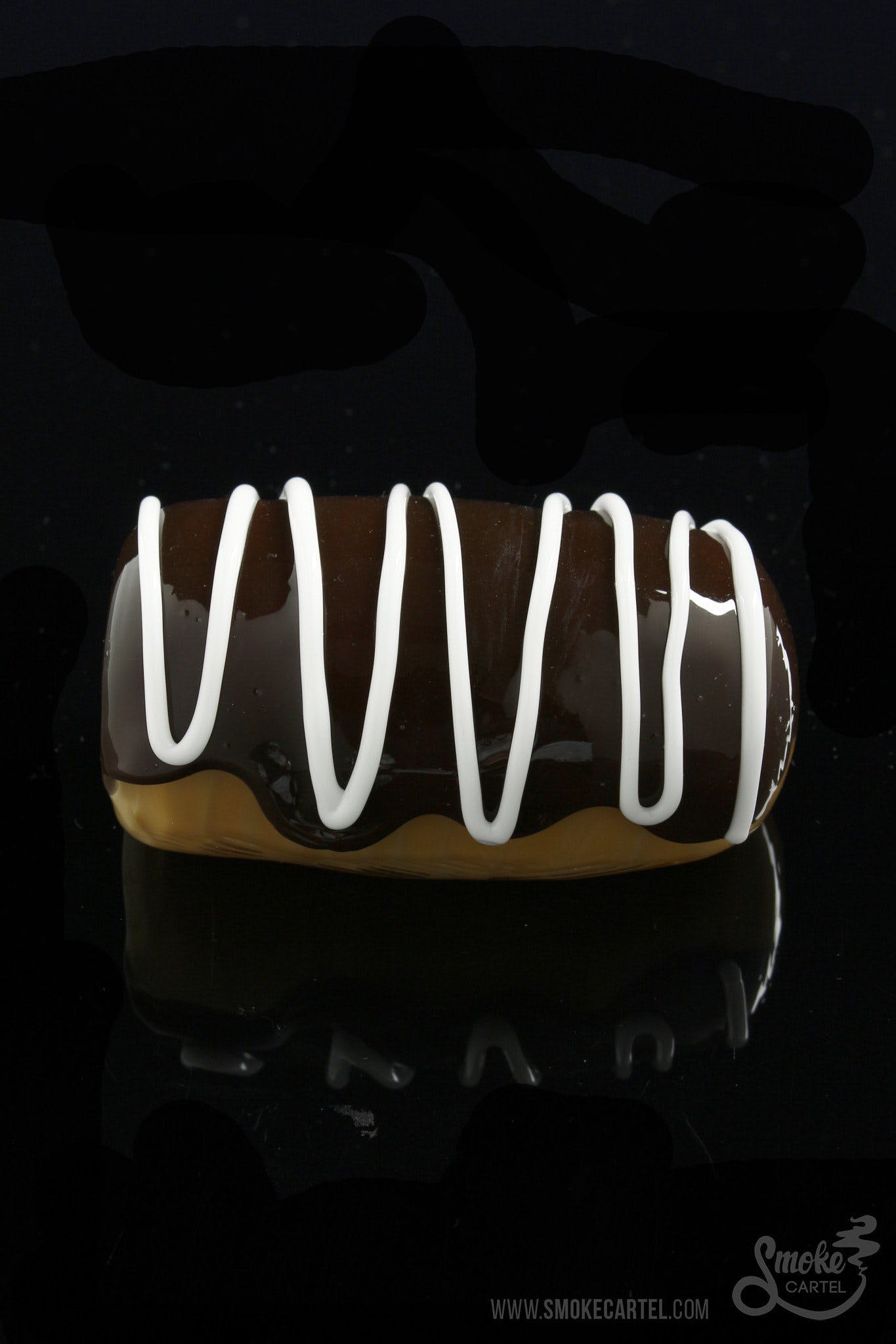 A close-up shot of the Glassheads "Sweet Eclair" Chillum on a dark surface, highlighting its smooth, curved glass design.