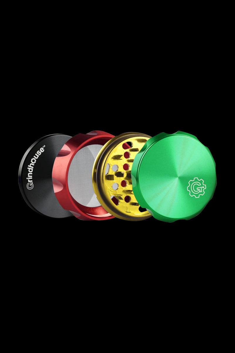 Angled close-up of a disassembled Pulsar Carver 4-Piece Grinder showing green, gold, red, and black stacked components on a black background