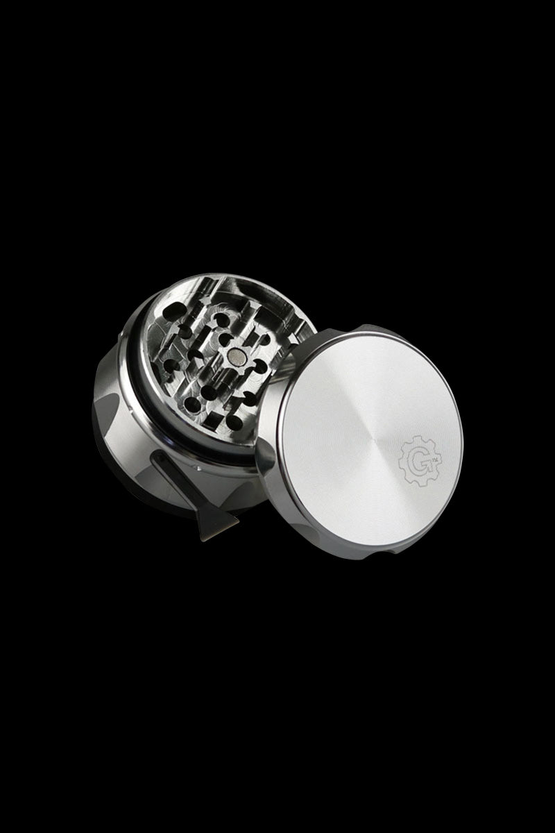 Angled close-up of the silver-black Pulsar Carver 4-Piece Grinder showing its open, toothed interior and smooth lid on a black background.