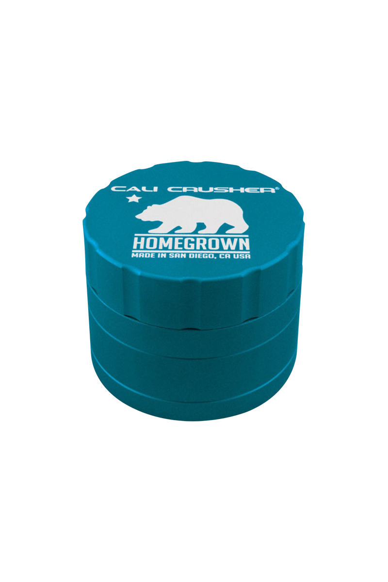 Close-up three-quarter view of a teal Cali Crusher Homegrown 4 Piece Grinder with white bear logo and layered ridged sides.